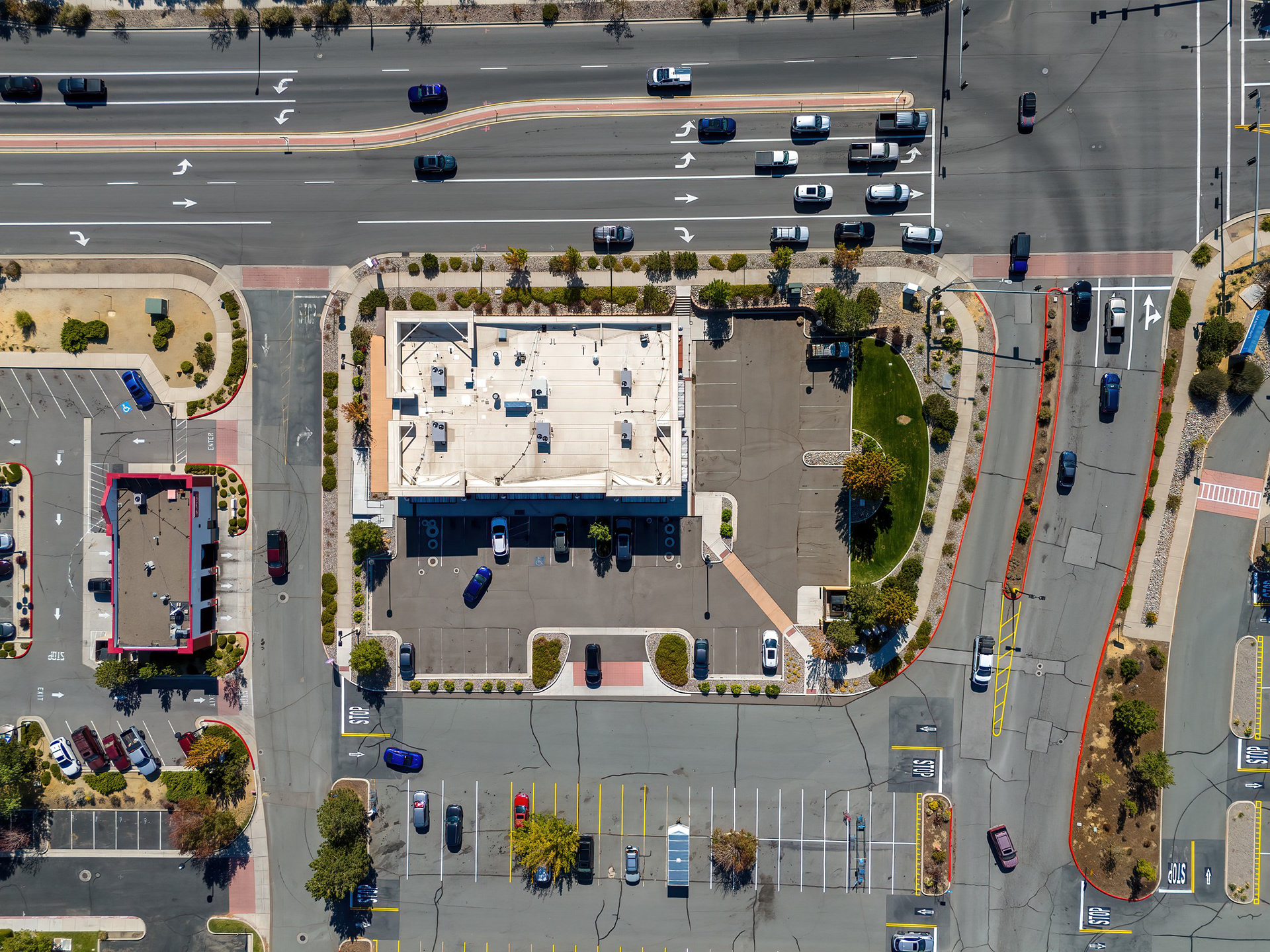 Top-down aerial of a retail pad building, parking, and intersection
