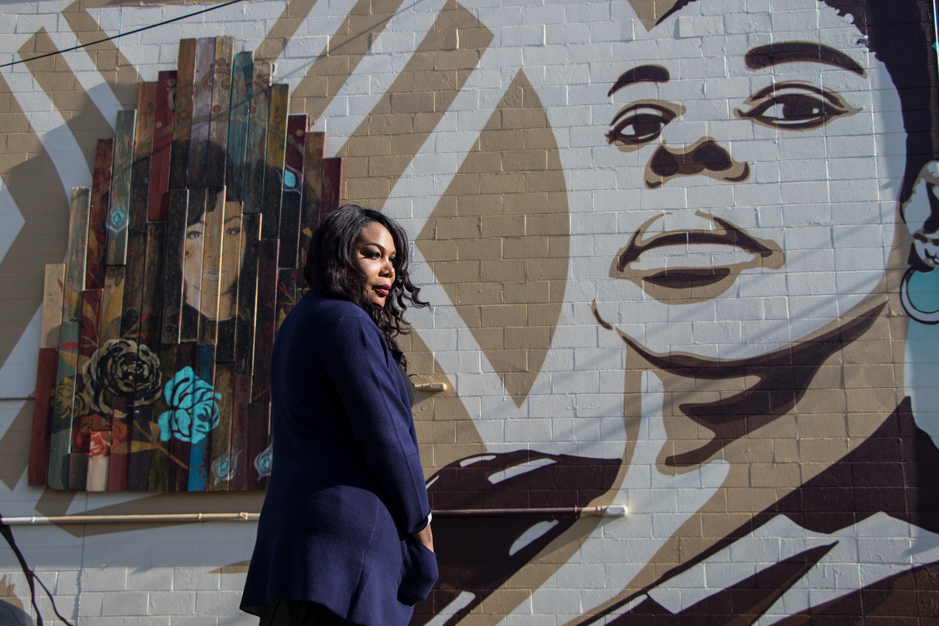 Activist Ebony Harper stands in front of the mural that she helped fund behind the Lavender Library in Sacramento, Calif. on Nov. 30, 2018.