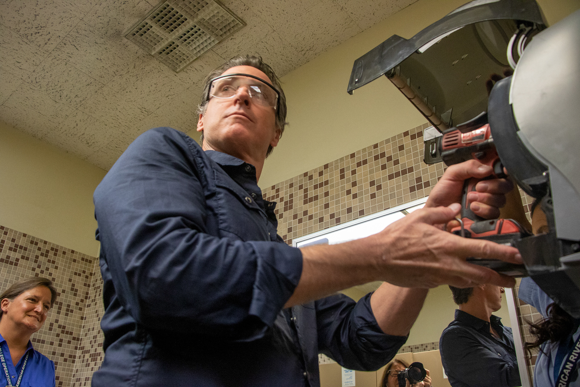 Governor Gavin Newsom assist Maria Arambula with replacing a paper towel dispenser at American River College during International Workers’ Day on May 1, 2019.. 
