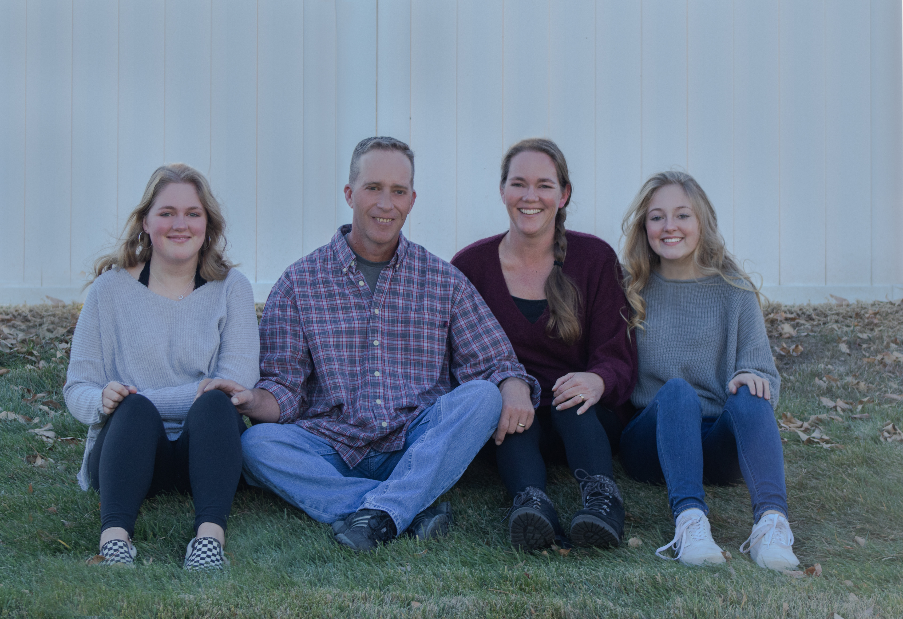 A family of four sitting on the grass for a family portrait