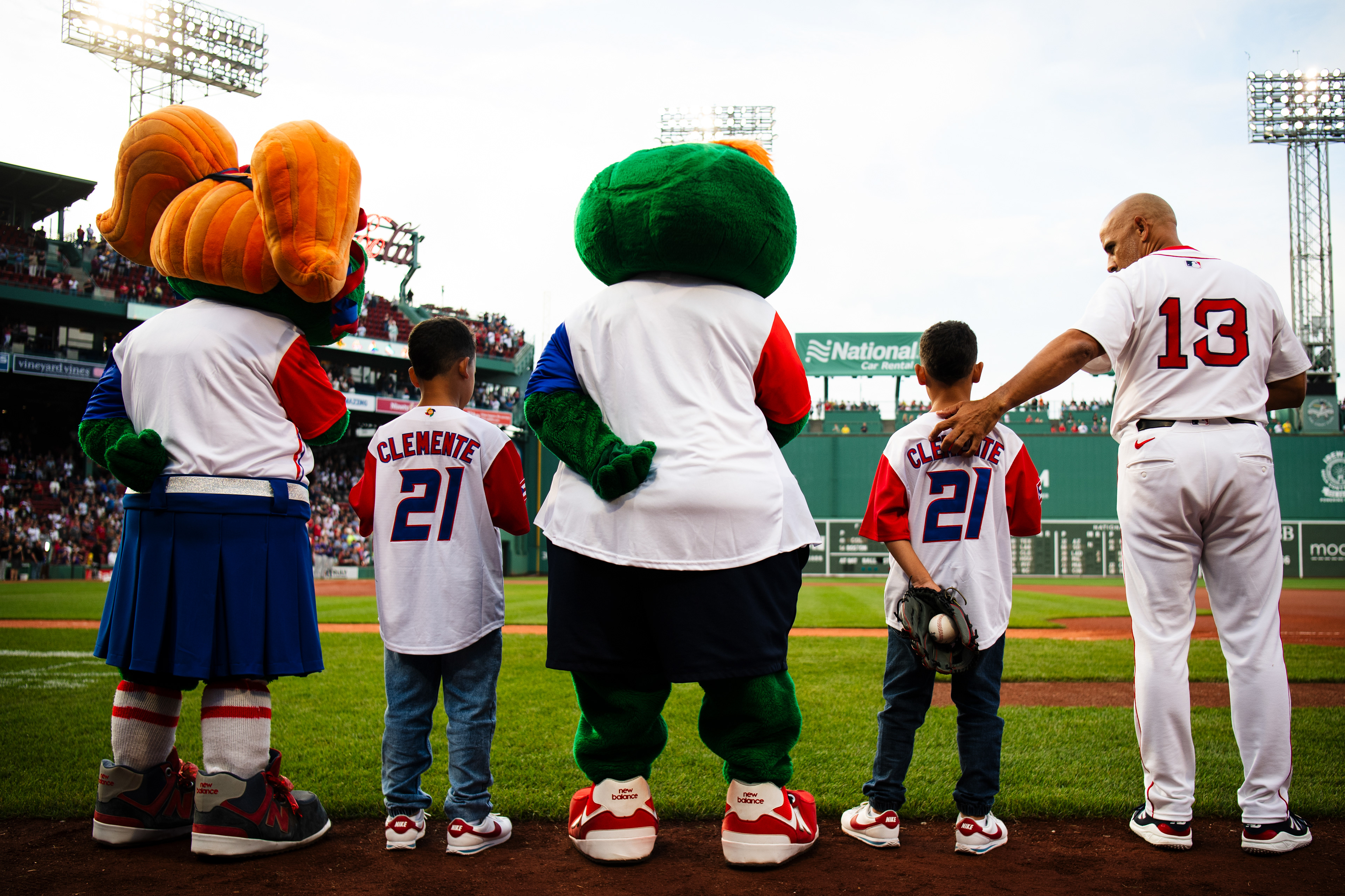 July 9, 2025, Boston, MA: Alex Cora #13 of the Boston Red Sox pulls his son closer during the National Anthem ahead of game between the Boston Red Sox and the Colorado Rockies at Fenway Park in Boston, Massachusetts Wednesday, July 9, 2025.  (Photo by Clay Stark/Boston Red Sox)