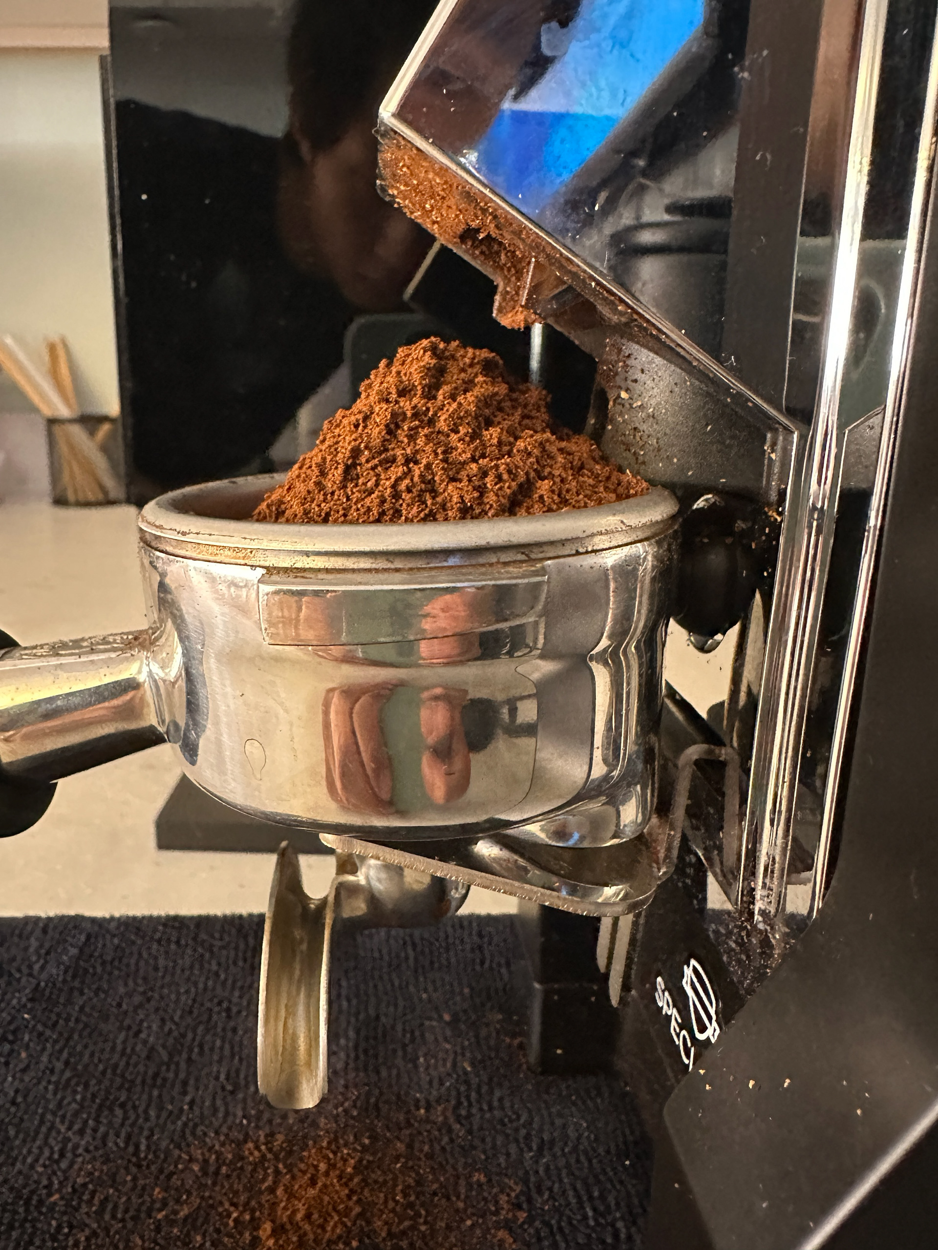 Grounds are deposited in a pile from the grinder