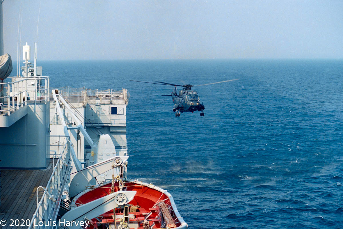 Royal Navy Sea King Helicopter exercising landing manouvres along side RFA Fort Grange