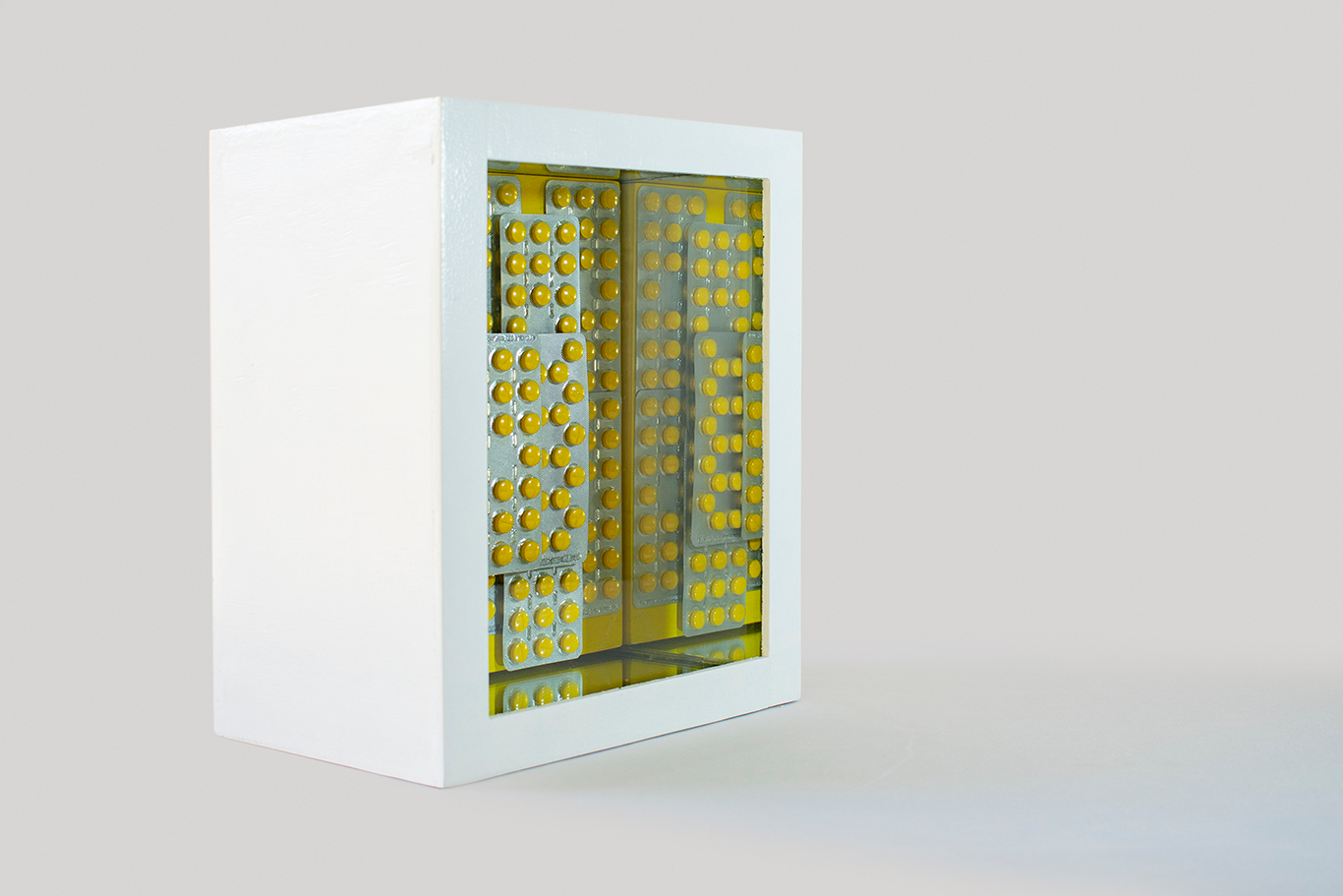 "AAA, Adiós Amarillo Antirreumático", Angélica Omaña,Ensamble de medicamentos caducados donados por pacientes de un hospital público en vitrina, 29 x 24 x 17 cm, 2020.