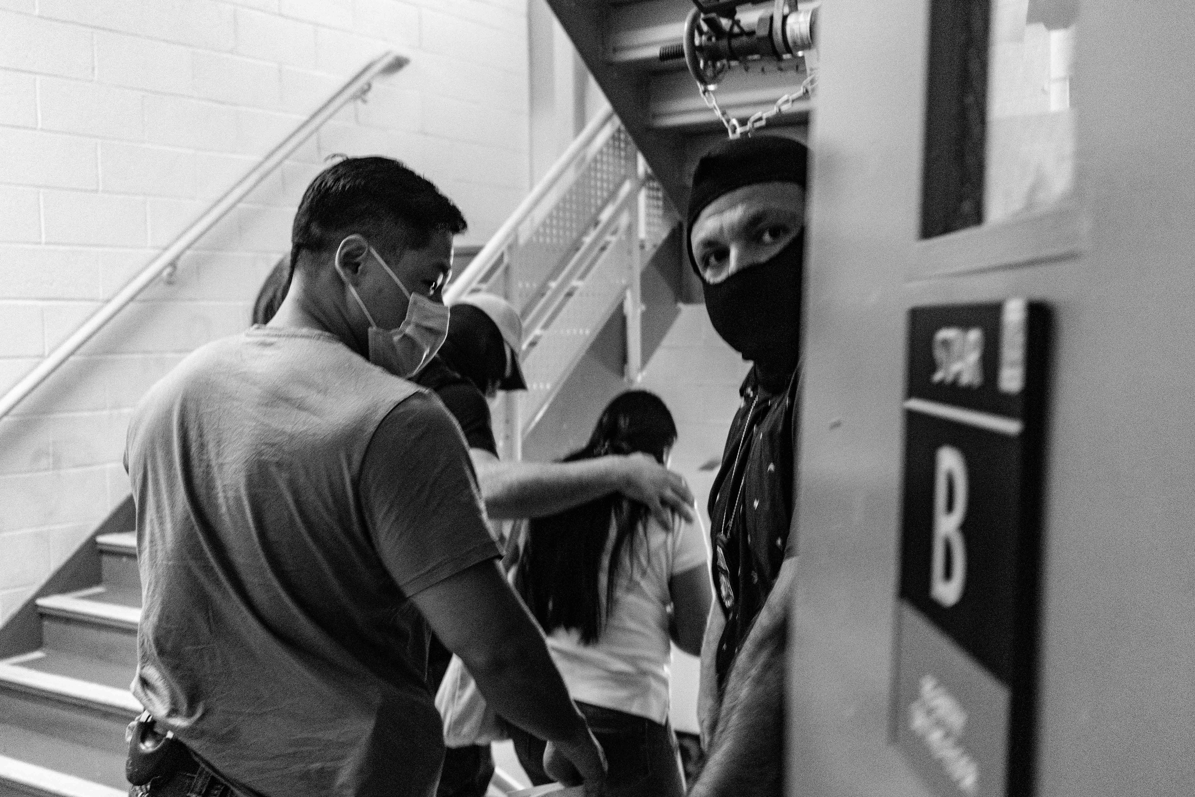 Federal agents detain and escort a respondent down the side stairwell. 
