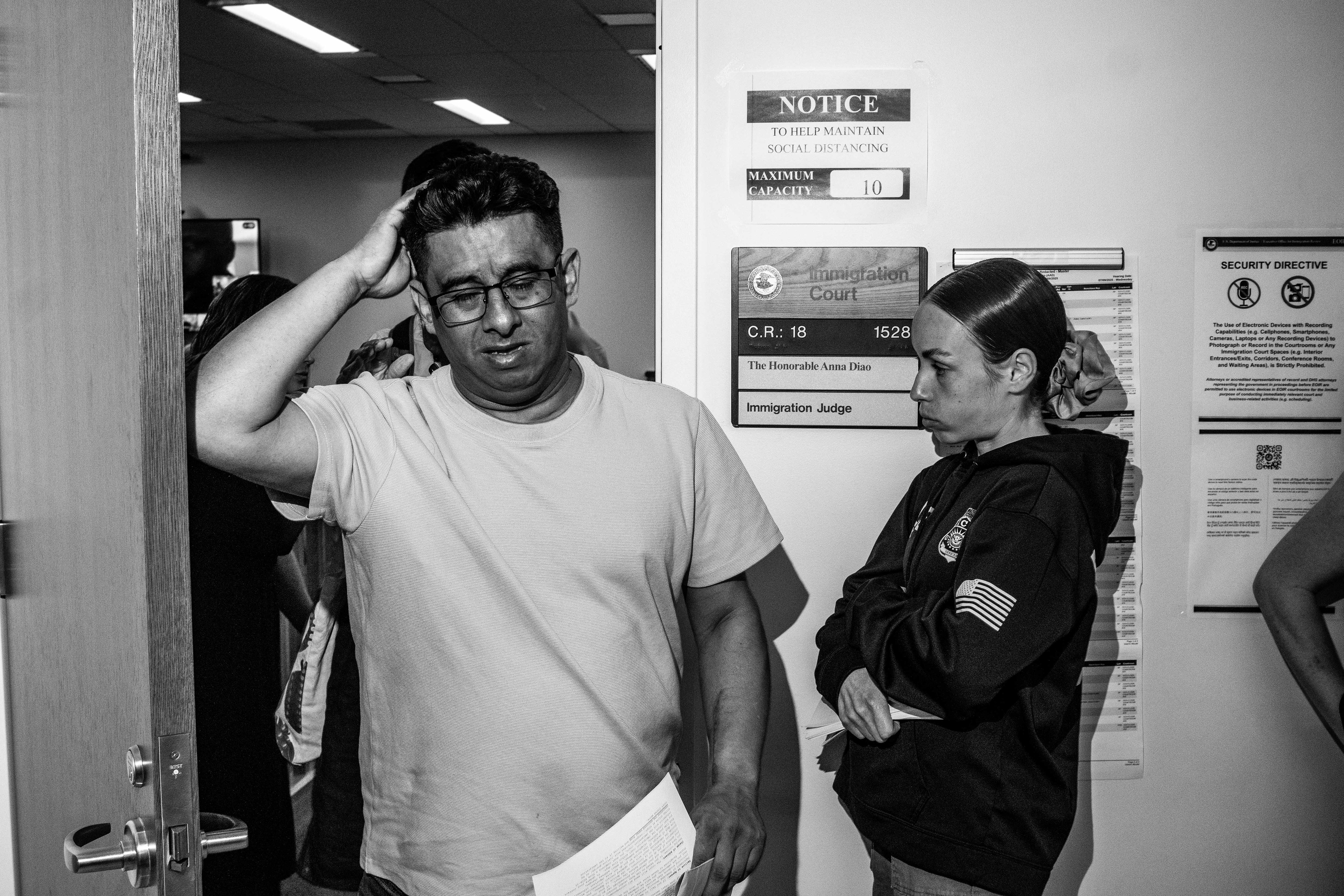 A migrant walks out of his hearing, waiting right outside is an ERO agent.