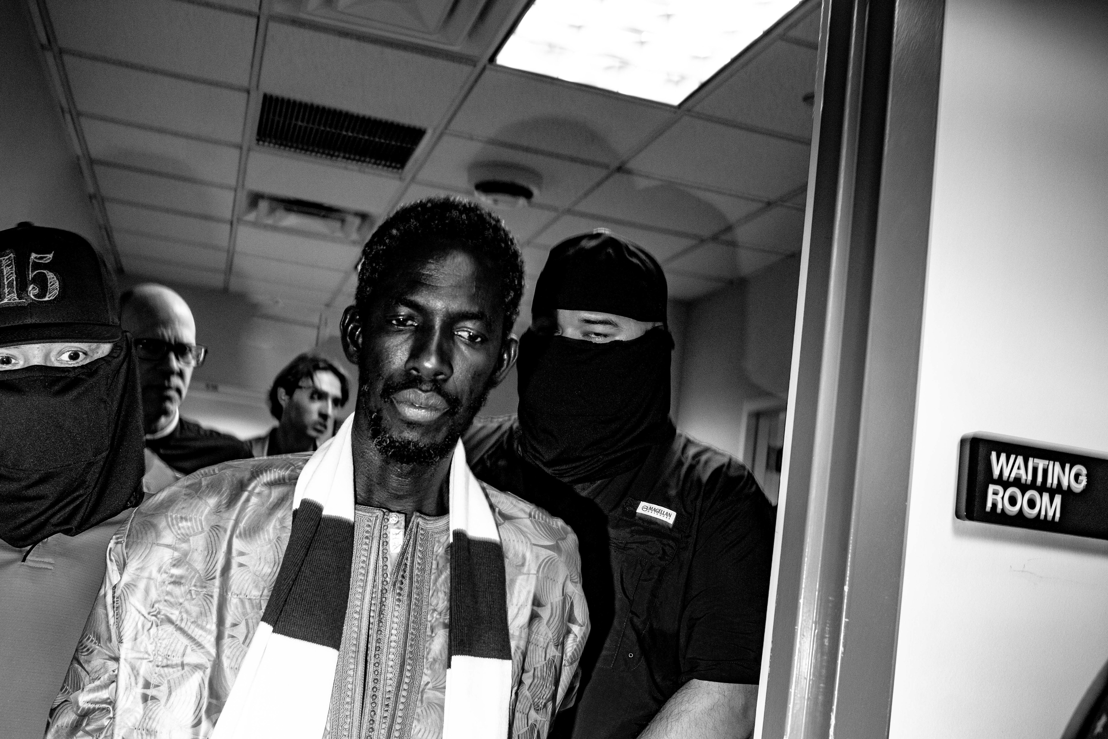 A respondent is detained and escorted out the waiting room by 2 federal agents.