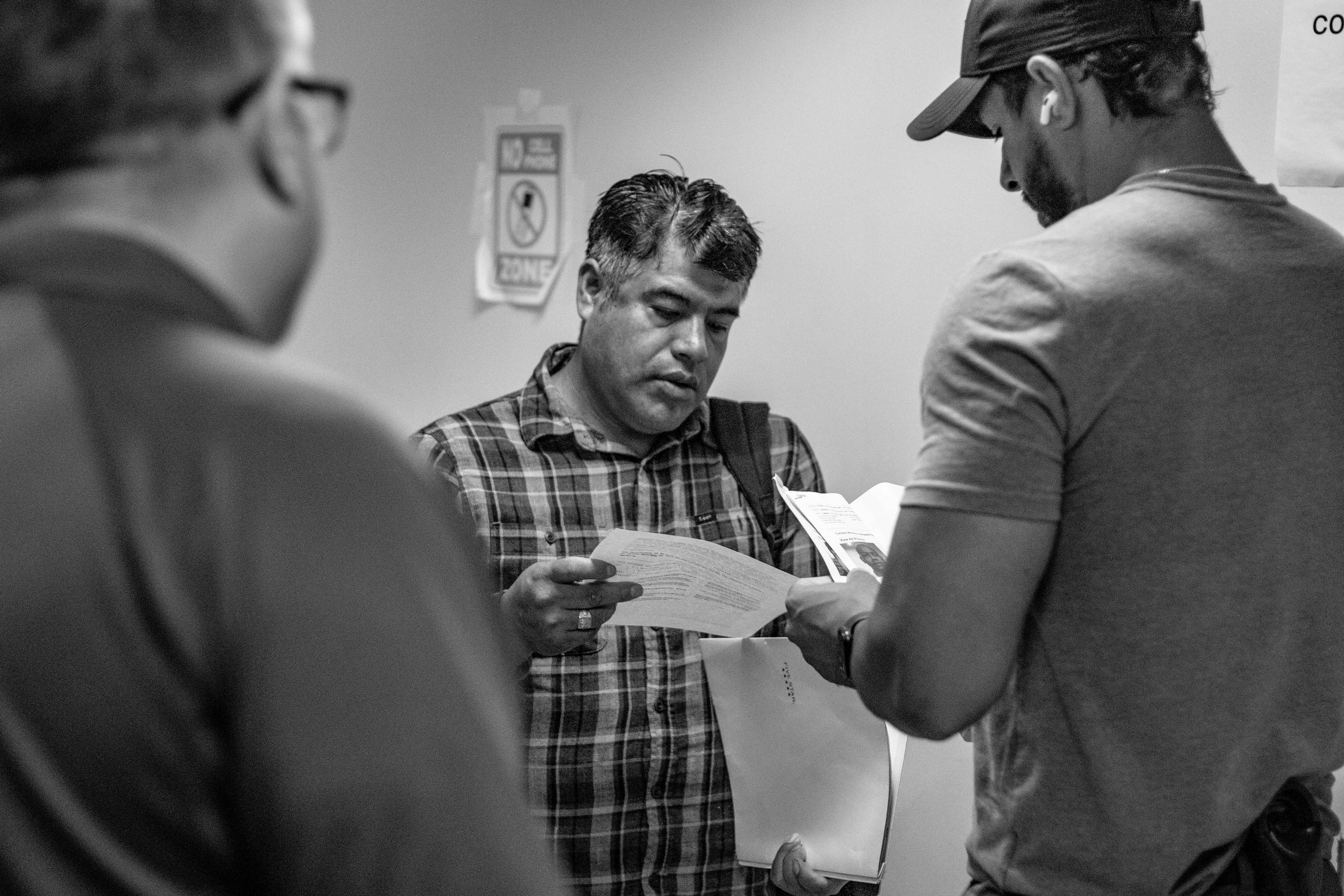 A federal agent reviews a man's immigration documents. This is common practice as agents have the paperwork of their "targets".