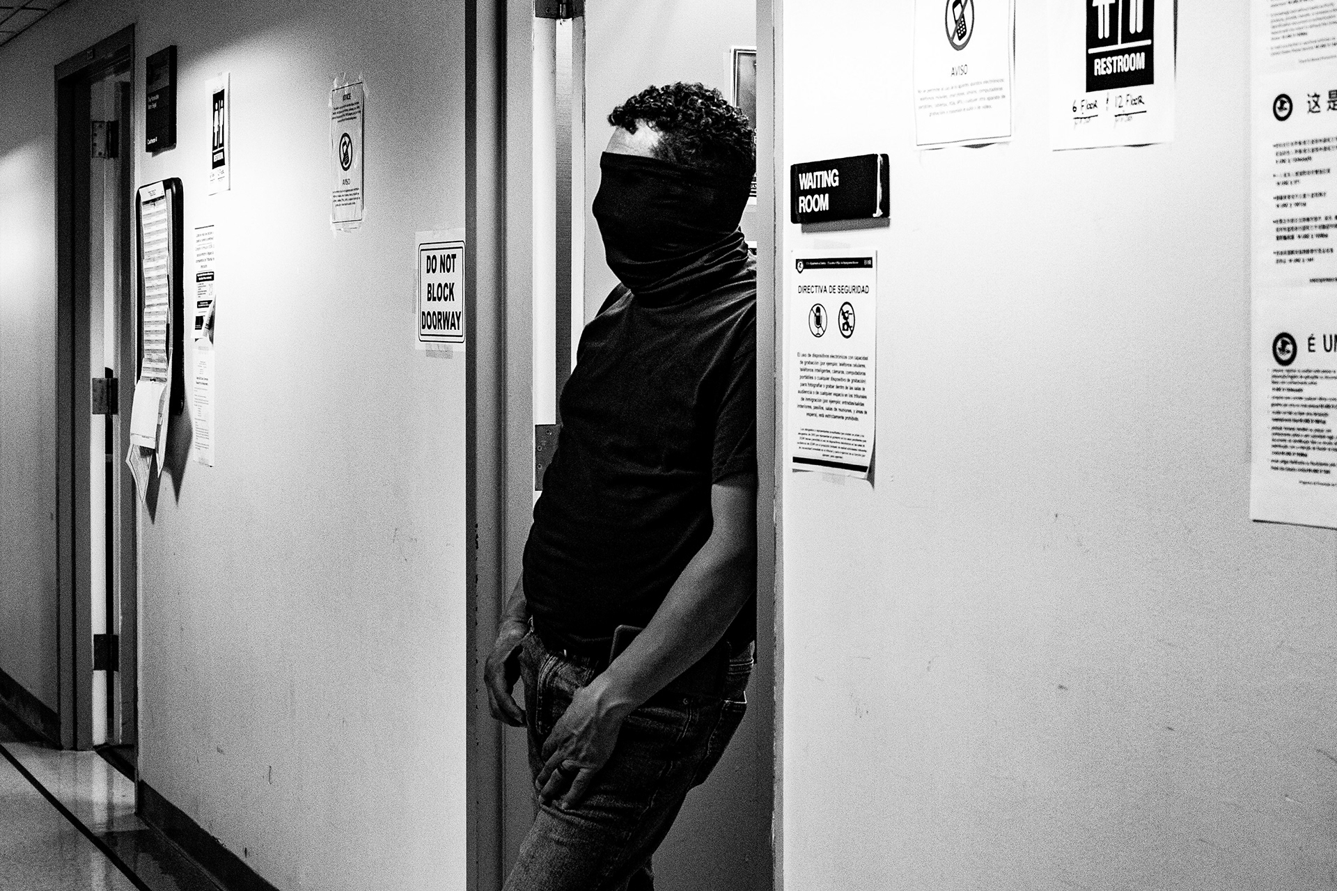 A border patrol agent waits outside a waiting room with his face fully covered by his mask.