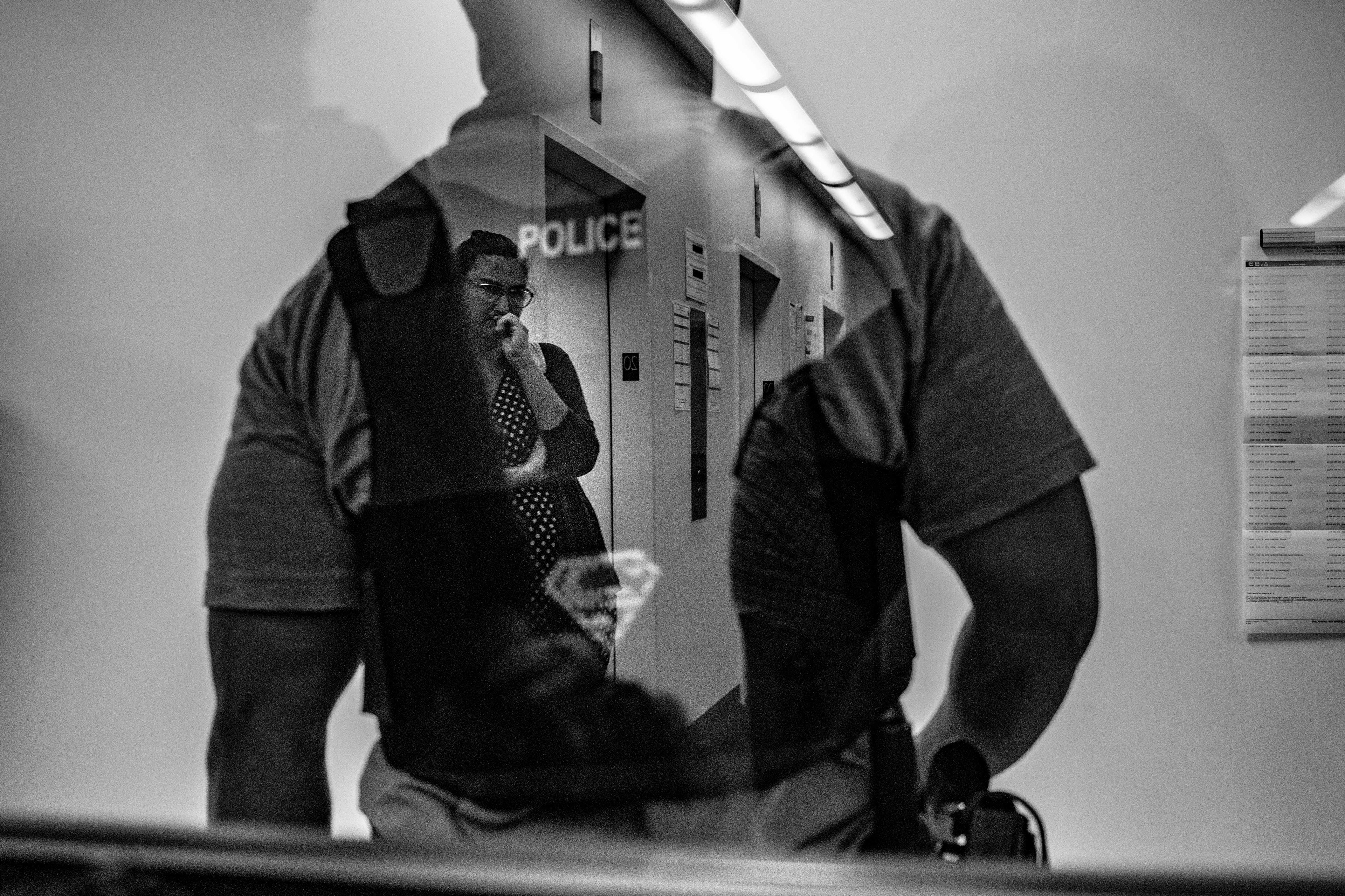A legal observer watches on as a federal agent waits in the hallways of 290 Broadway, a building next to 26 Federal Plaza which also holds immigration courts.