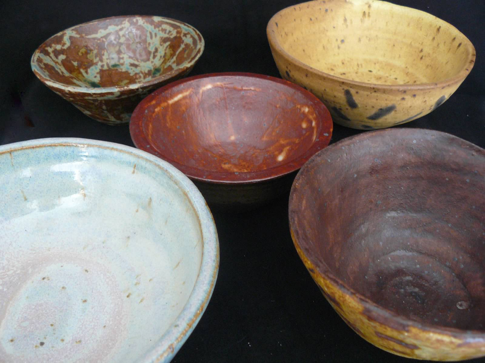 ceramic bowls of various warm colored glazes and patterns