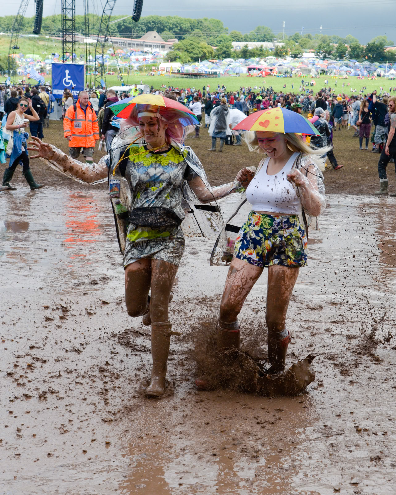 Pilton, UK, 27/06/2014 : Atmosphere at Glastonbury Festival. 2 young girls run though a large muddy puddle. Picture by Julie Edwards
