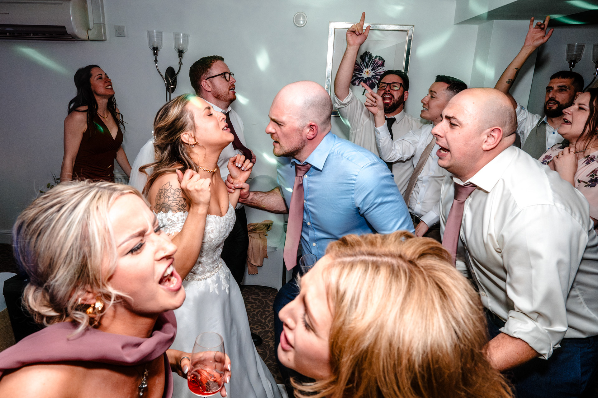 A bride and groom dance surrounded by friends.