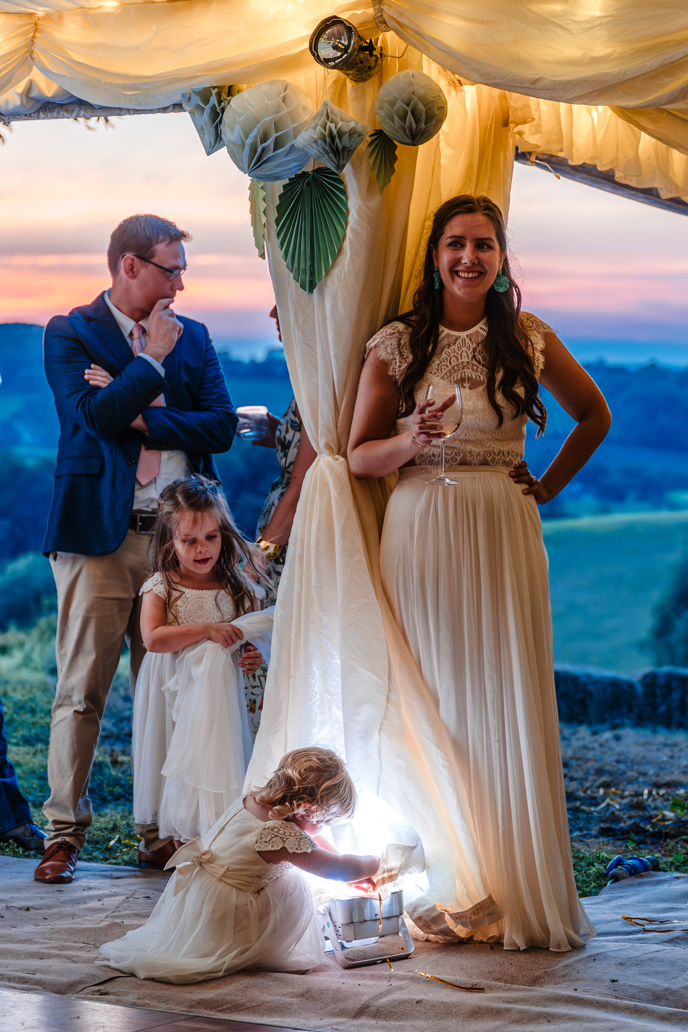 A bride watches the speeches during sunset at her wedding.