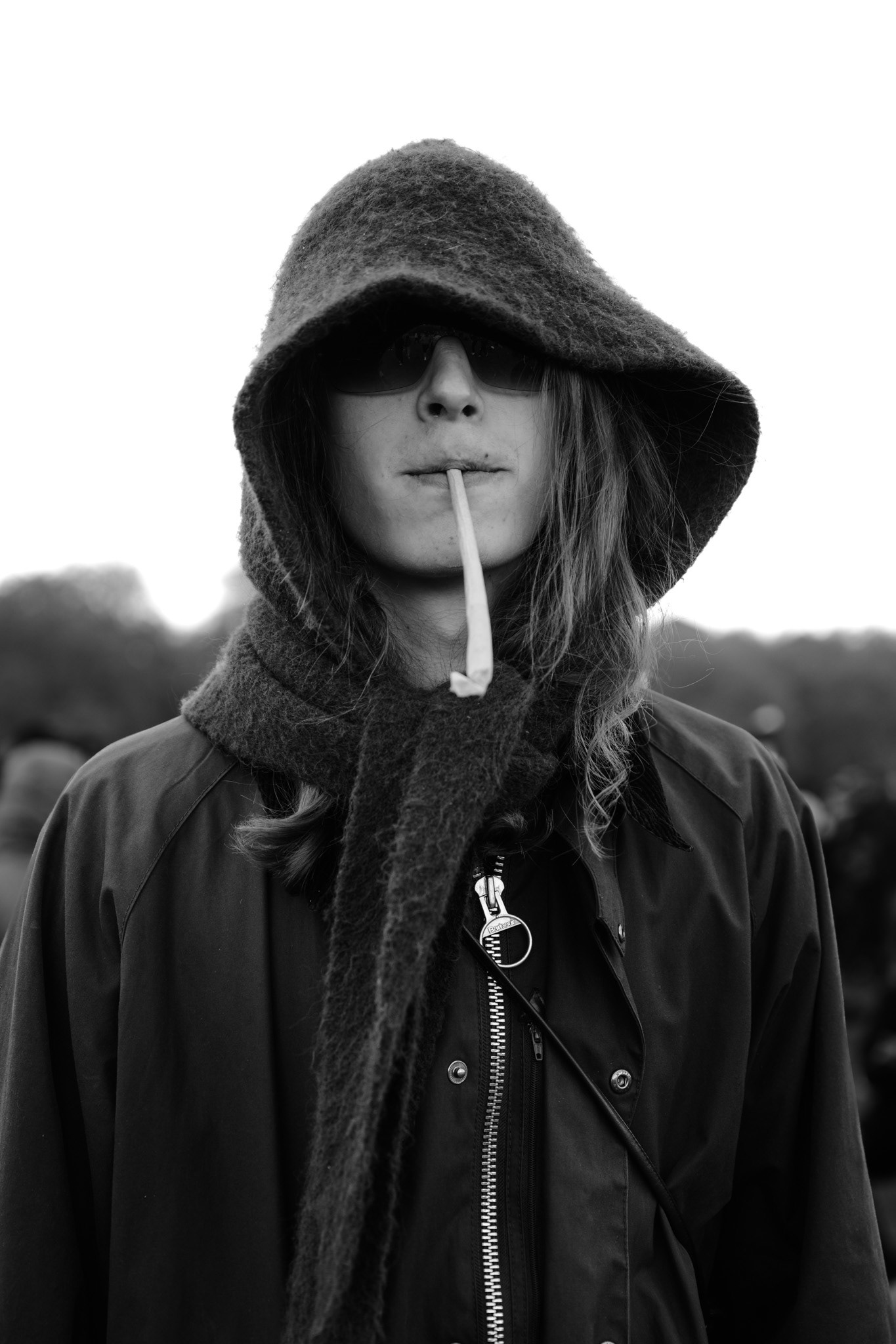 A cloaked and hooded man smokes a joint.