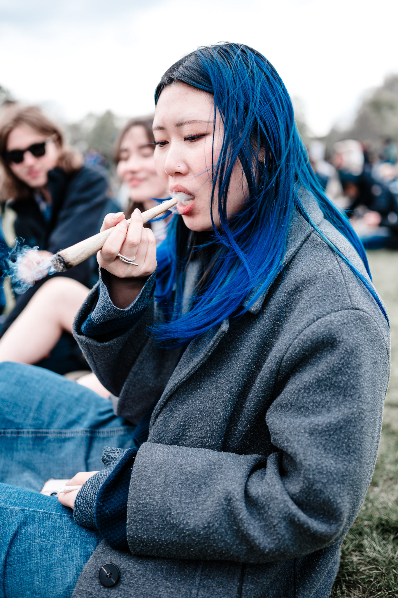A woman with blue hair takes a puff from a mega joint.