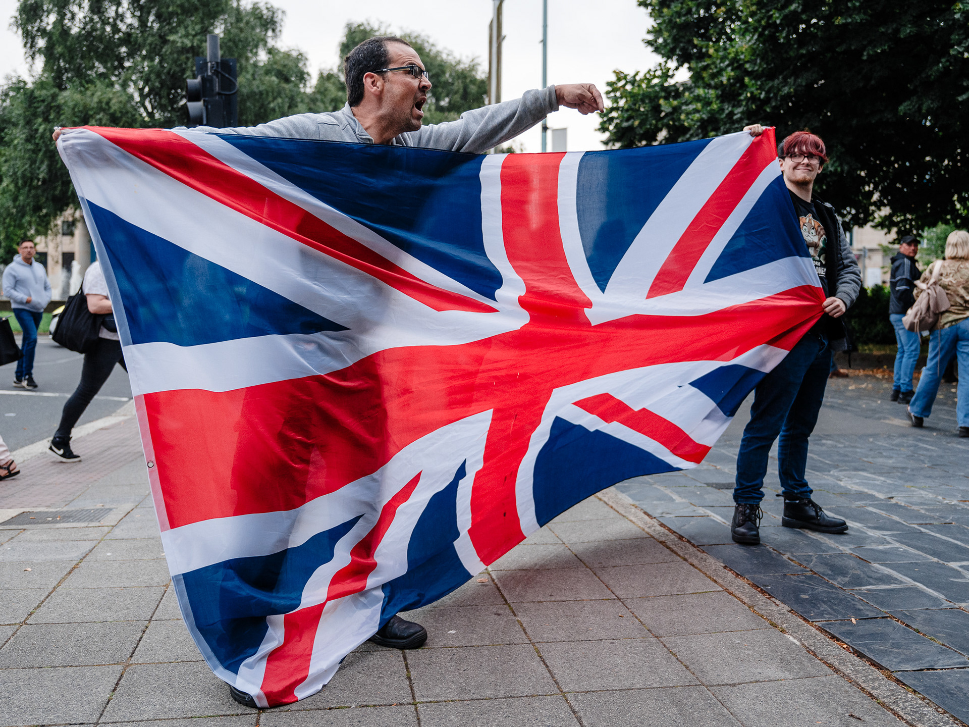 A shouting protester holds the Union Jack flag aloft yet upside down.