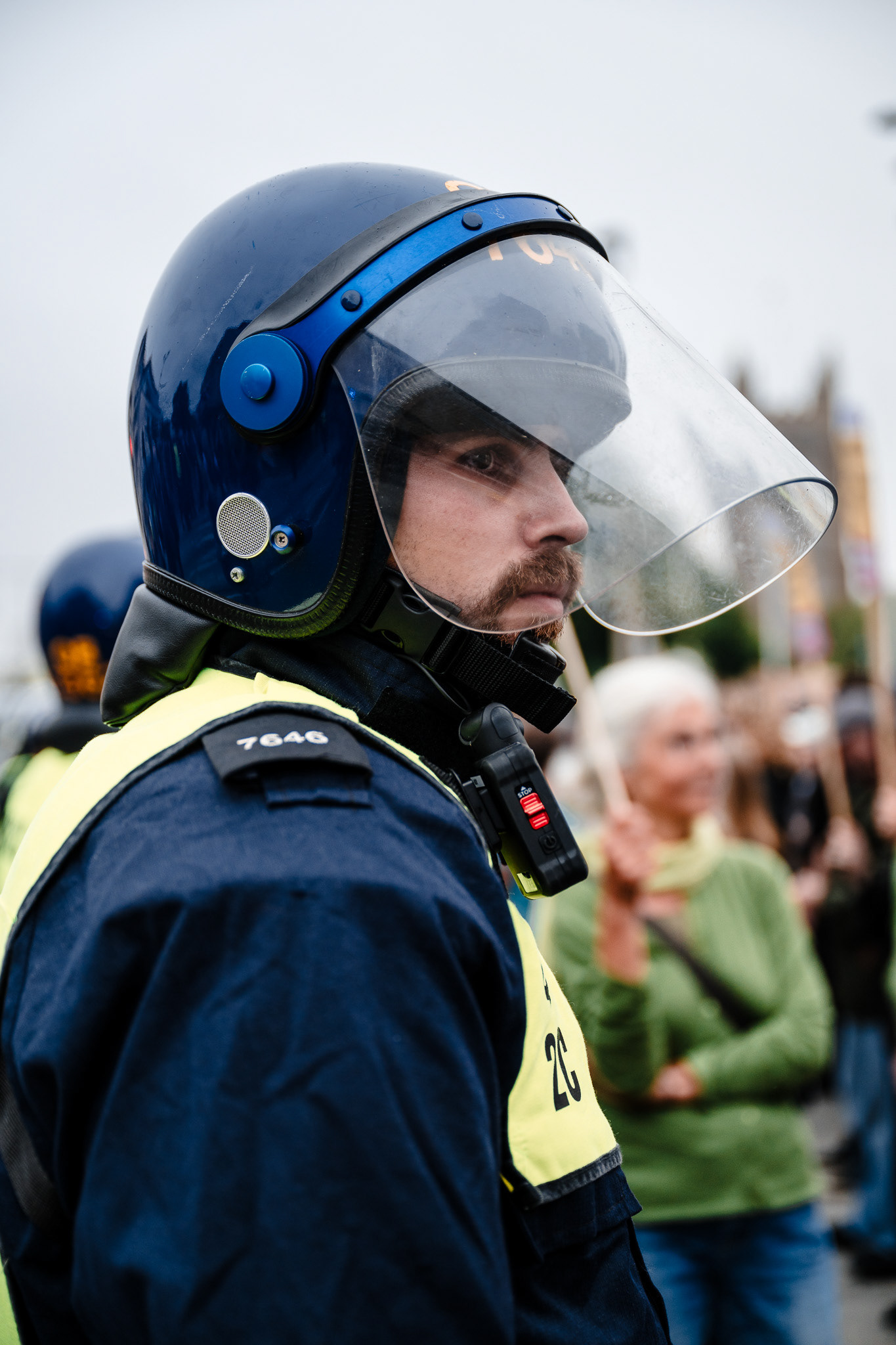 A police officer in riot grear and helmet looks anxiously at the protesters.