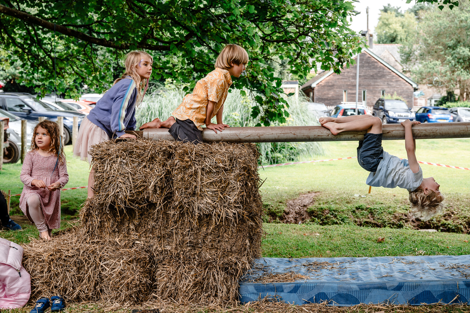 Children play in hay bales at a Devon church fete.