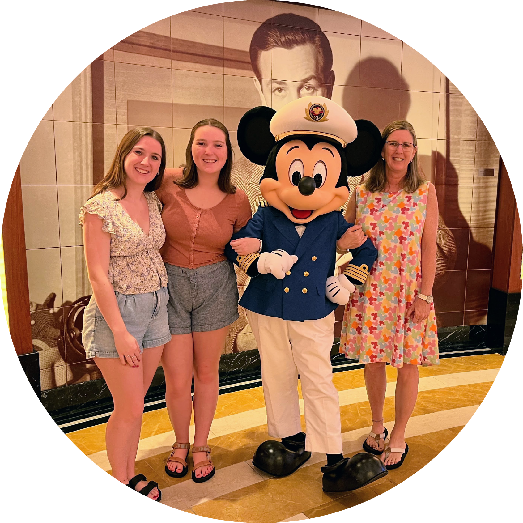 Two young adult daughters and their mother standing with Captain Mickey Mouse on the Disney Cruise Ship.
