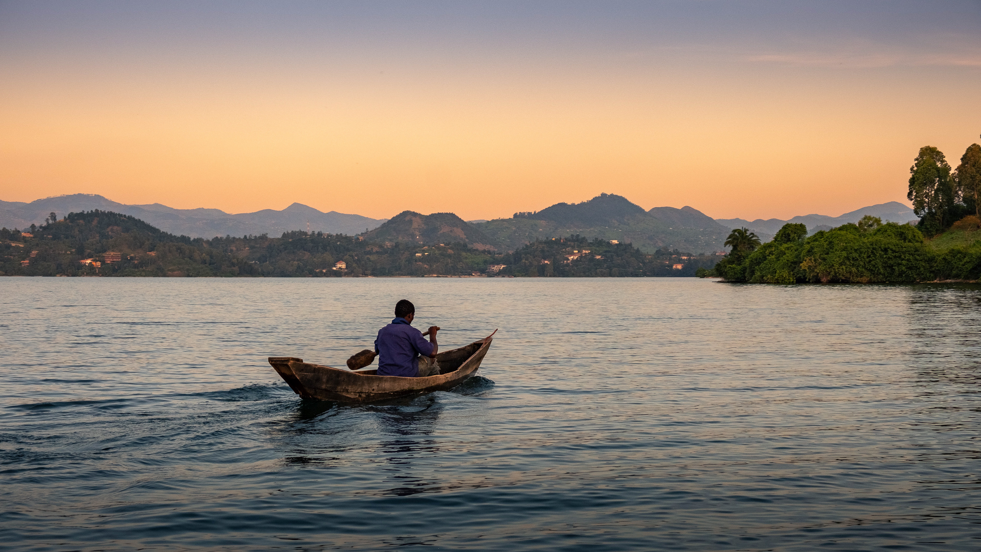 Man rowing towards sunset