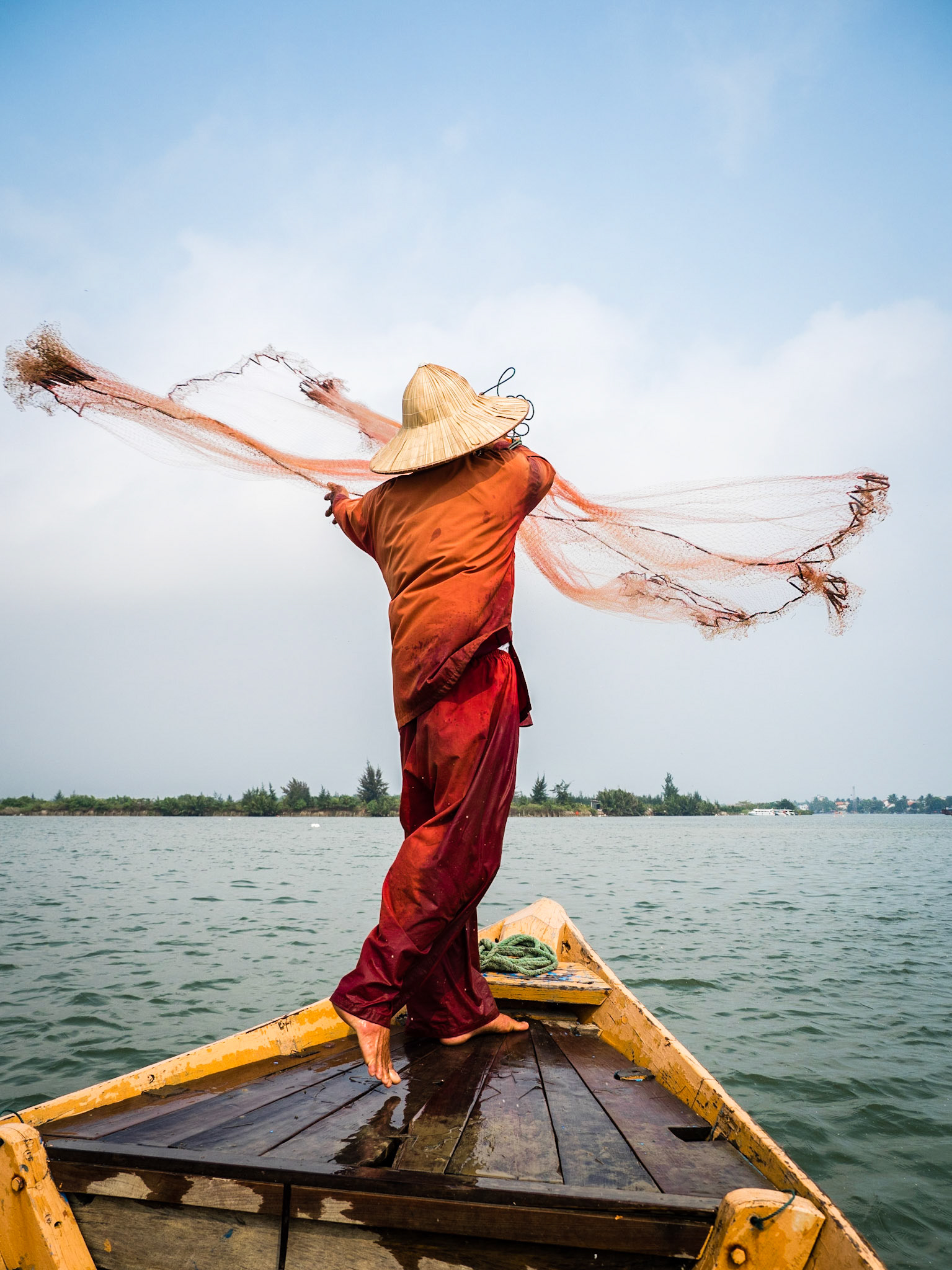 Local fisherman in Hoi An Vietnam casting fishing net from fishing boat