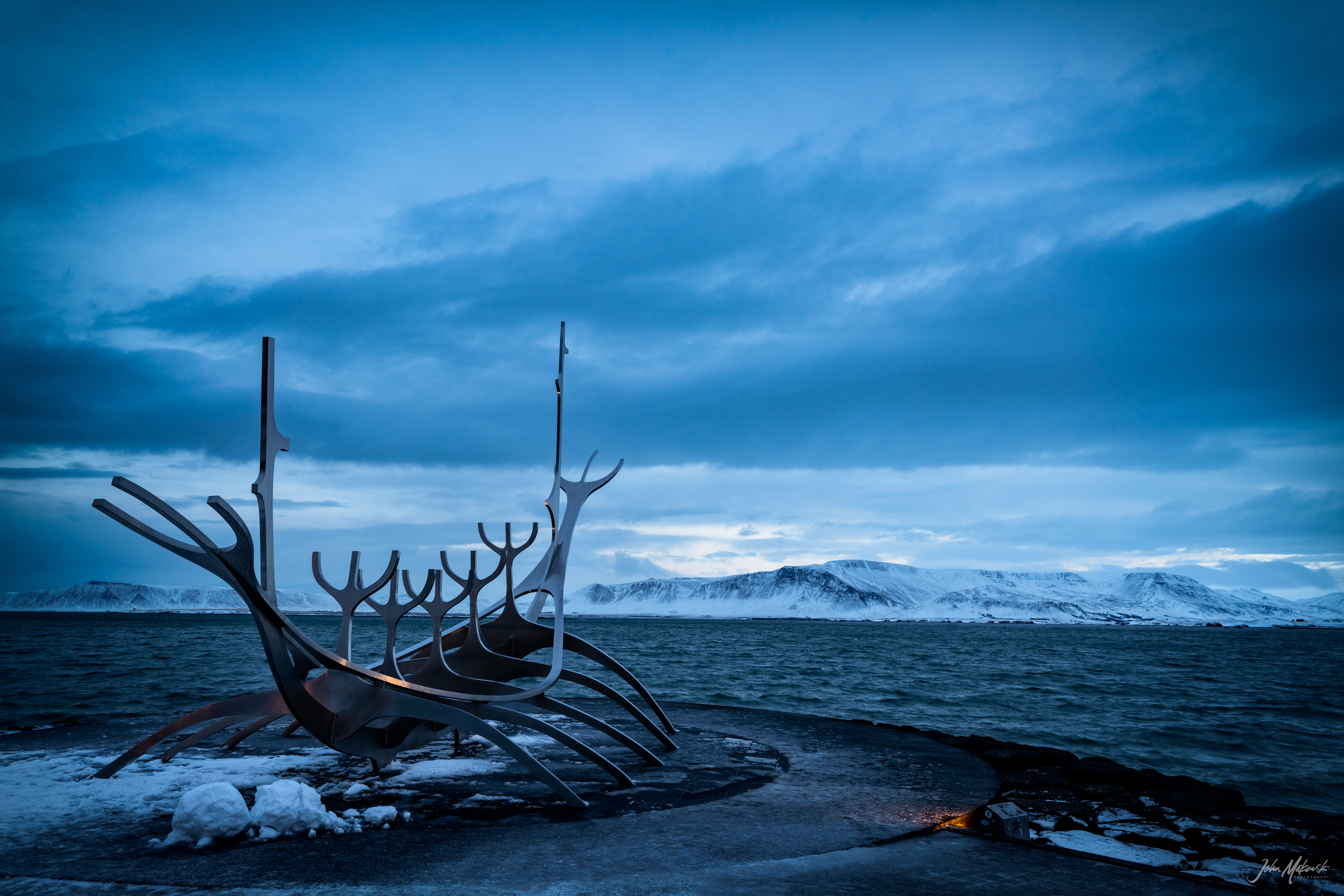 Solfarid (Sun Voyager) sculpture at sunrise on the bay at Reykjavik with Mount Esja in the background.  The sculpture represents a dream boat and an ode to the sun. It represents the promise of undiscovered territory and a dream of hope, progress and freedom.