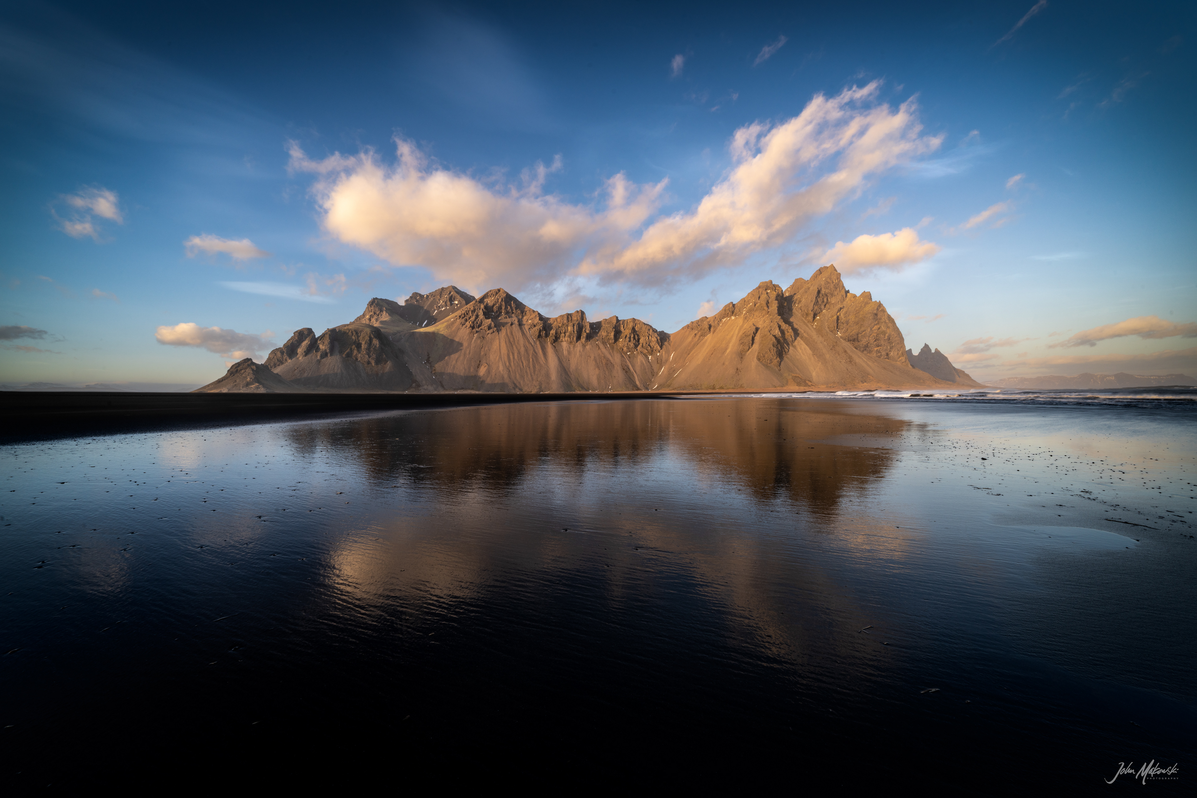 Vestrahorn reflected in the wet black sand beach