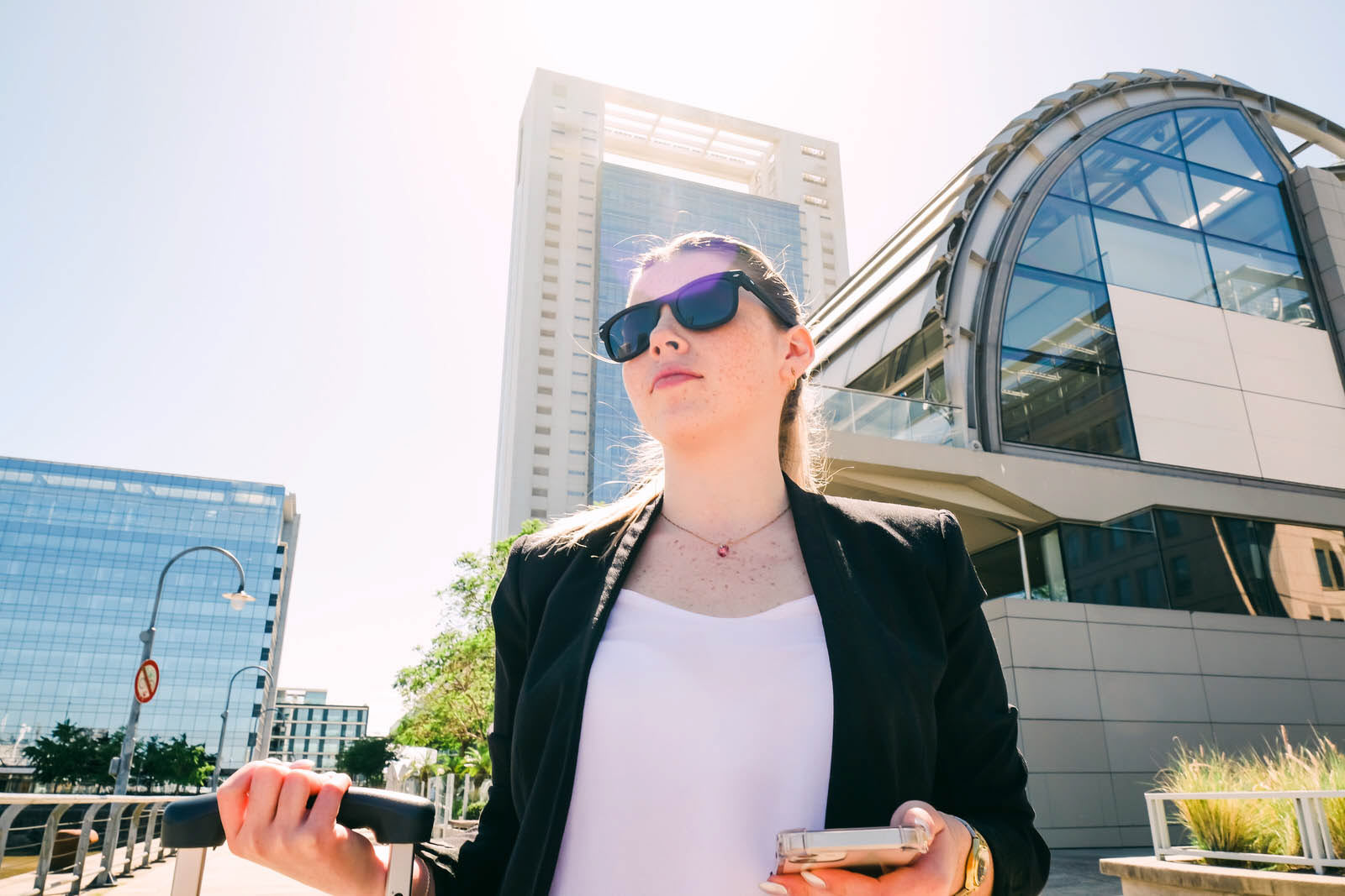Business woman with luggage standing in a modern city area, travel and mobility concept
