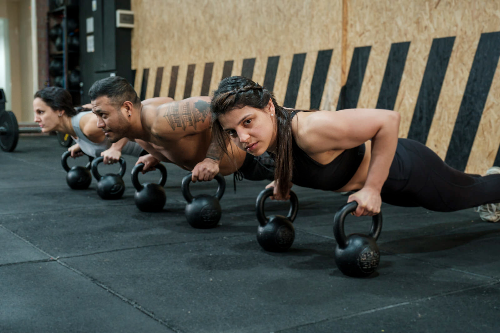 Group of athletes doing push-ups on kettlebells during a workout