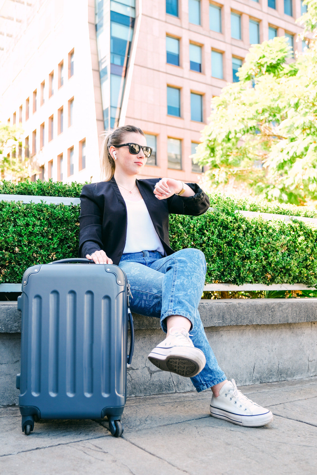 Woman with suitcase waiting outdoors and checking the time