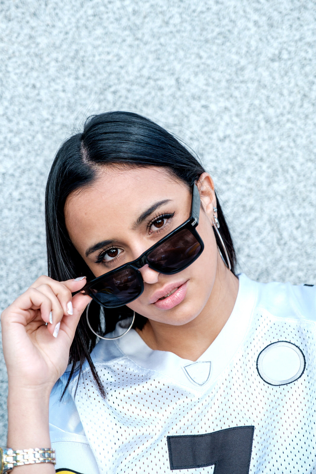 Confident young woman adjusting sunglasses, close-up portrait