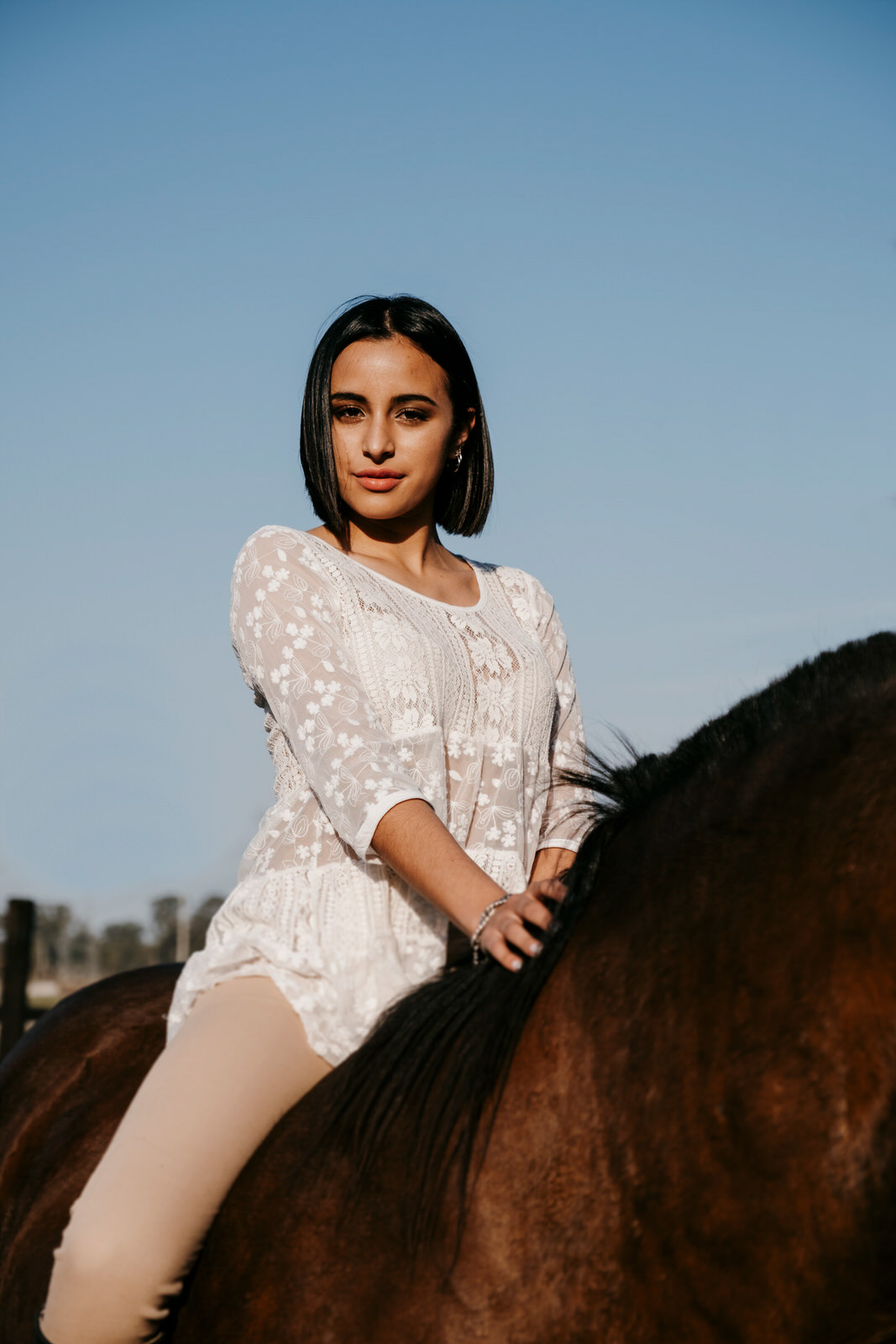 Woman riding a horse outdoors on a sunny day