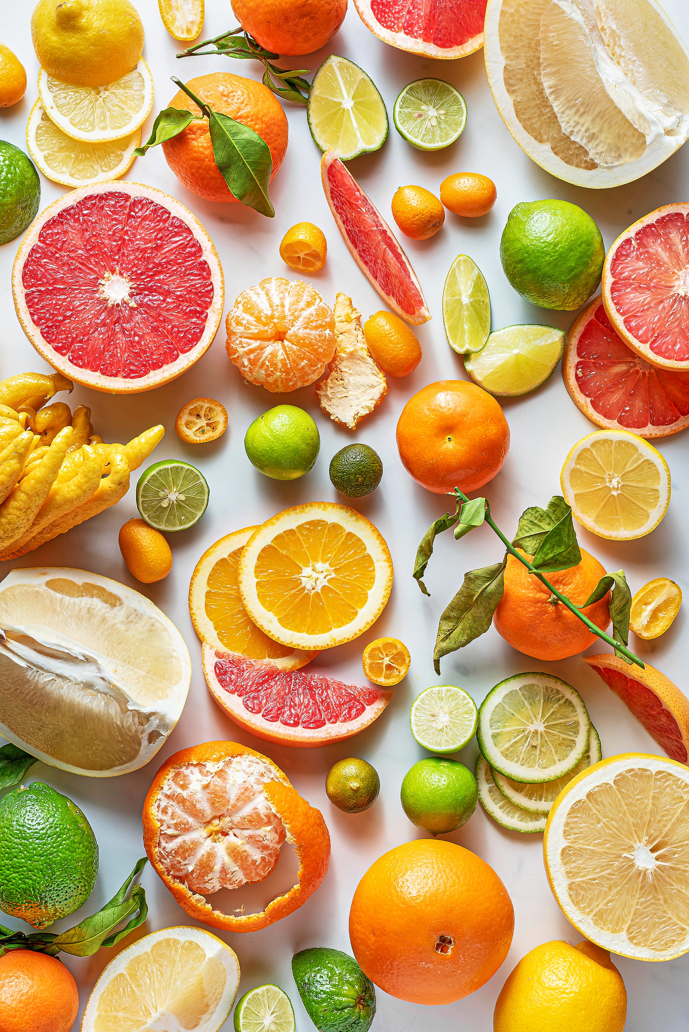 Bright and airy food photography showing every different variety of citrus fruits on a marble background