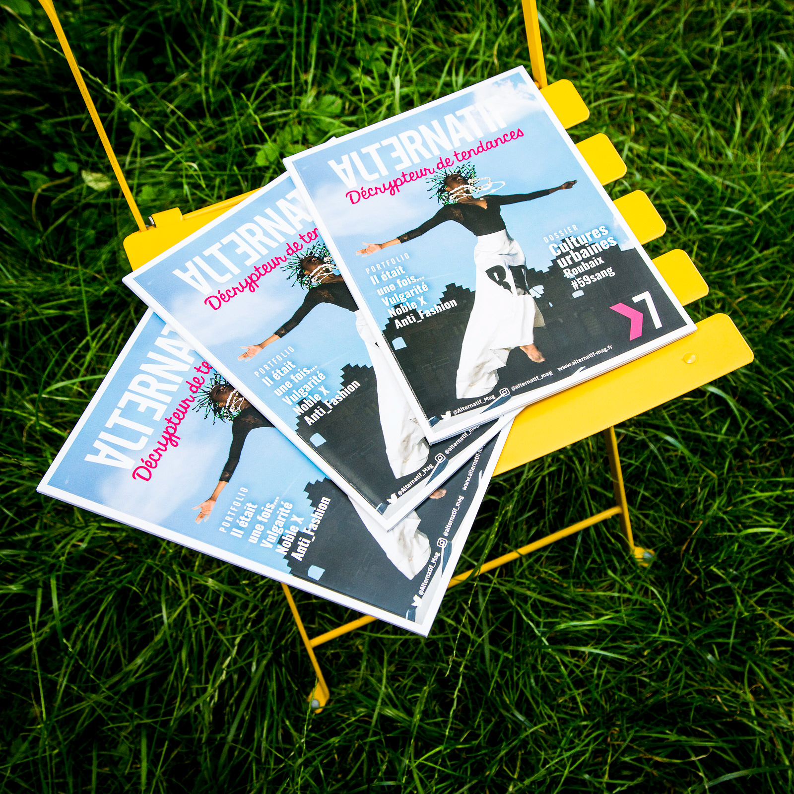 Couverture du magazine Alternatif numéro 7. Trois magazines disposés sur une chaise de jardin jaune installée dans un jardin..