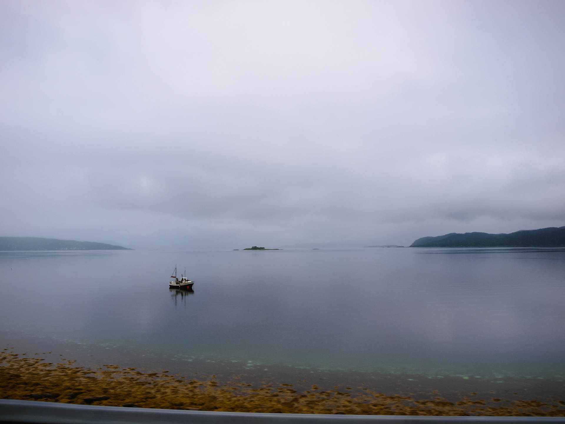 A lone fishing boat bobs in the shallows near the road on the drive north to Tromso