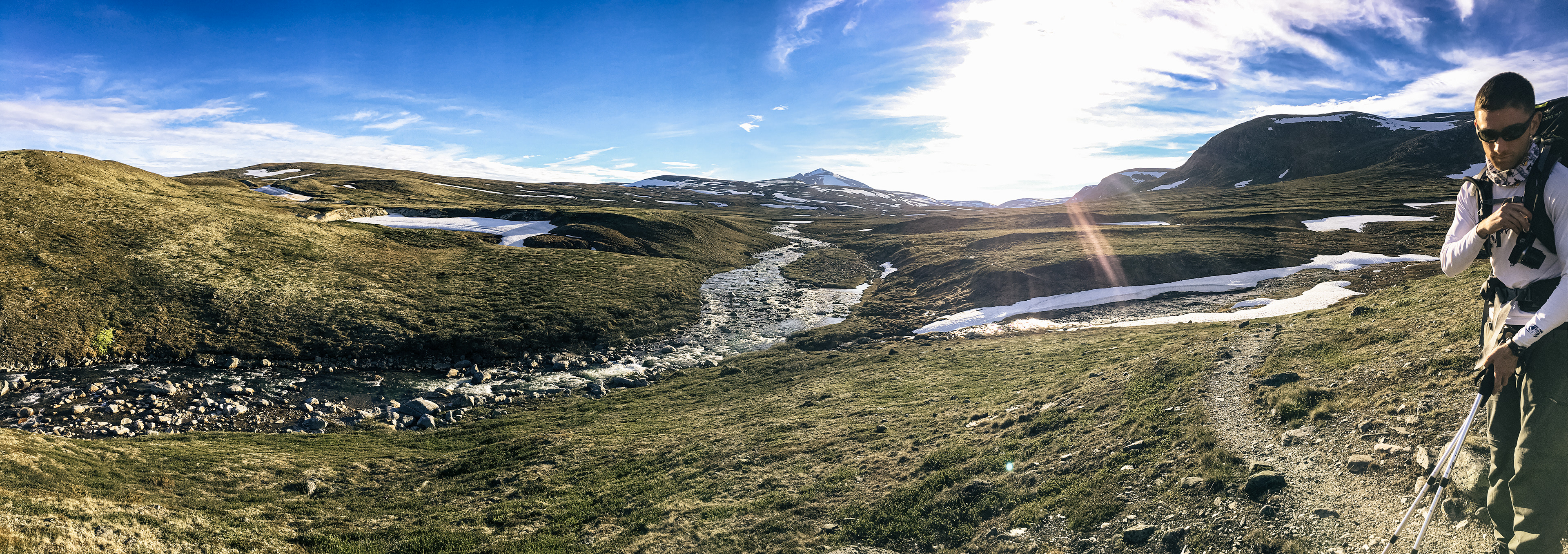 A panorama showcasing a mountain stream as Rob endures the bright sun in Dovrefjell-Sunndalsfjella Nasjonalpark