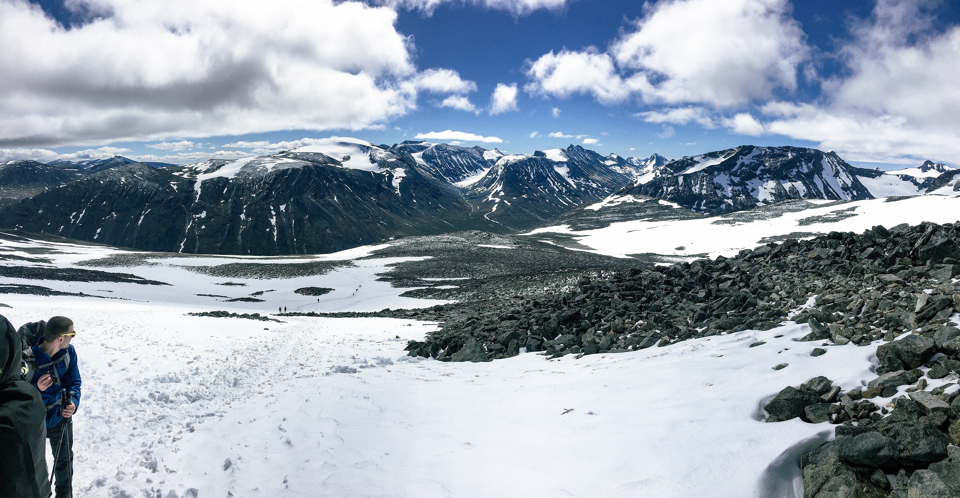 Nick pauses to enjoy the cool mountain air. Photos struggle to capture the sheer scale of the landscape, but you can see tiny silhouettes of hikers further down the trail.