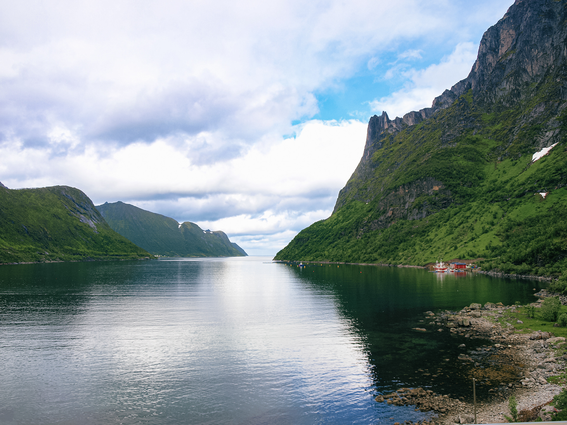 A classic Norwegian landscape of fishing boats near steep peaks right up to the water's edge in Senja