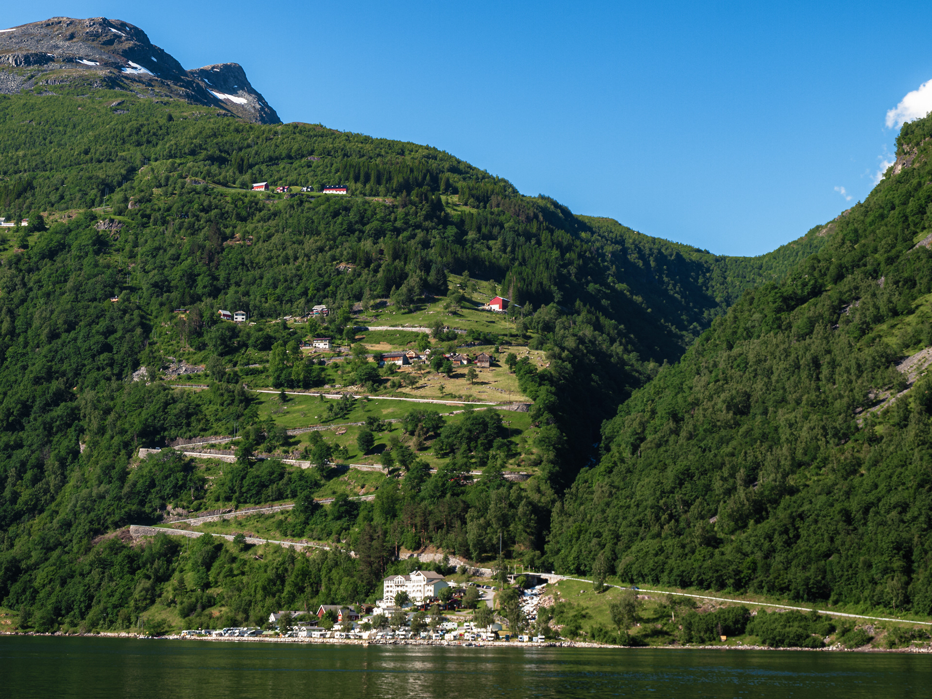Sharp turns of a mountain road, with homes built confidently on the steep slope, a common sight amongts Norway's many fjords