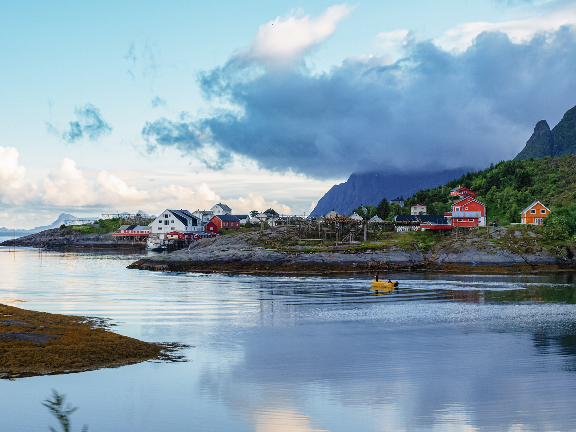 Two people use a small yellow motorboat to travel between islands in Reine, Lofoten