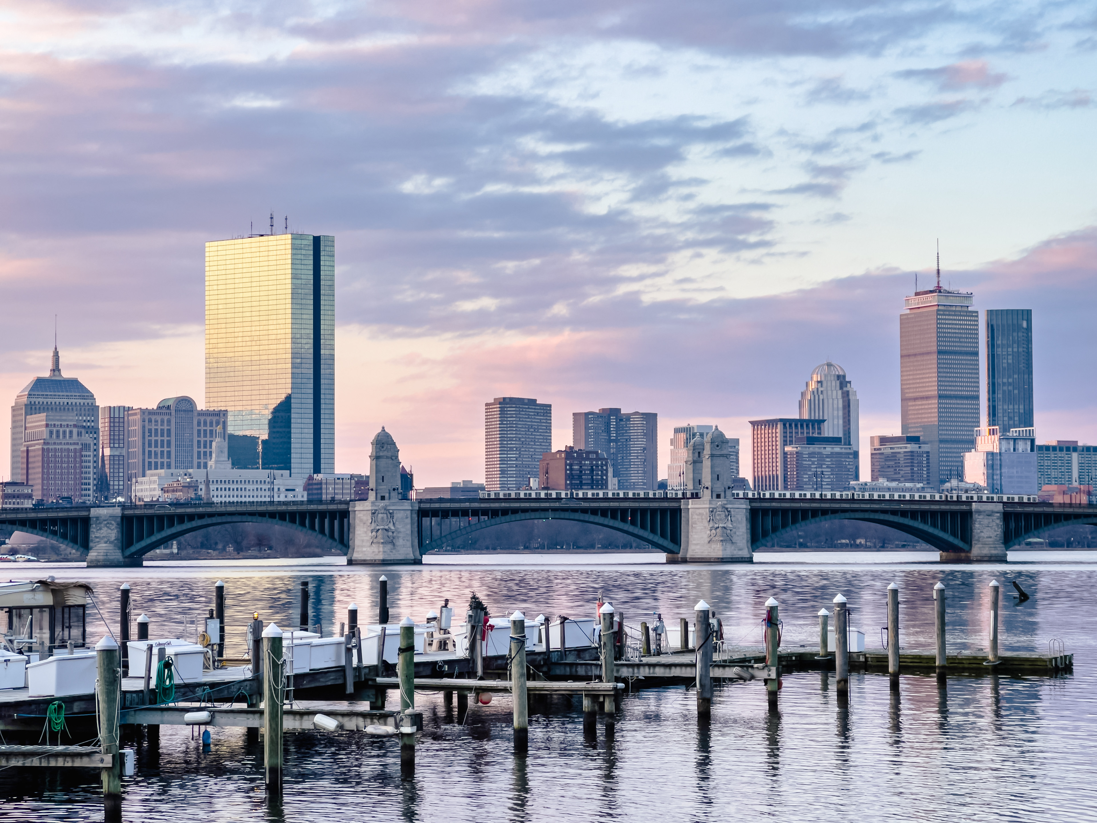 A vivid February sunrise illuminates Boston's skyline as a red line train crosses over the Charles River into Cambridge.