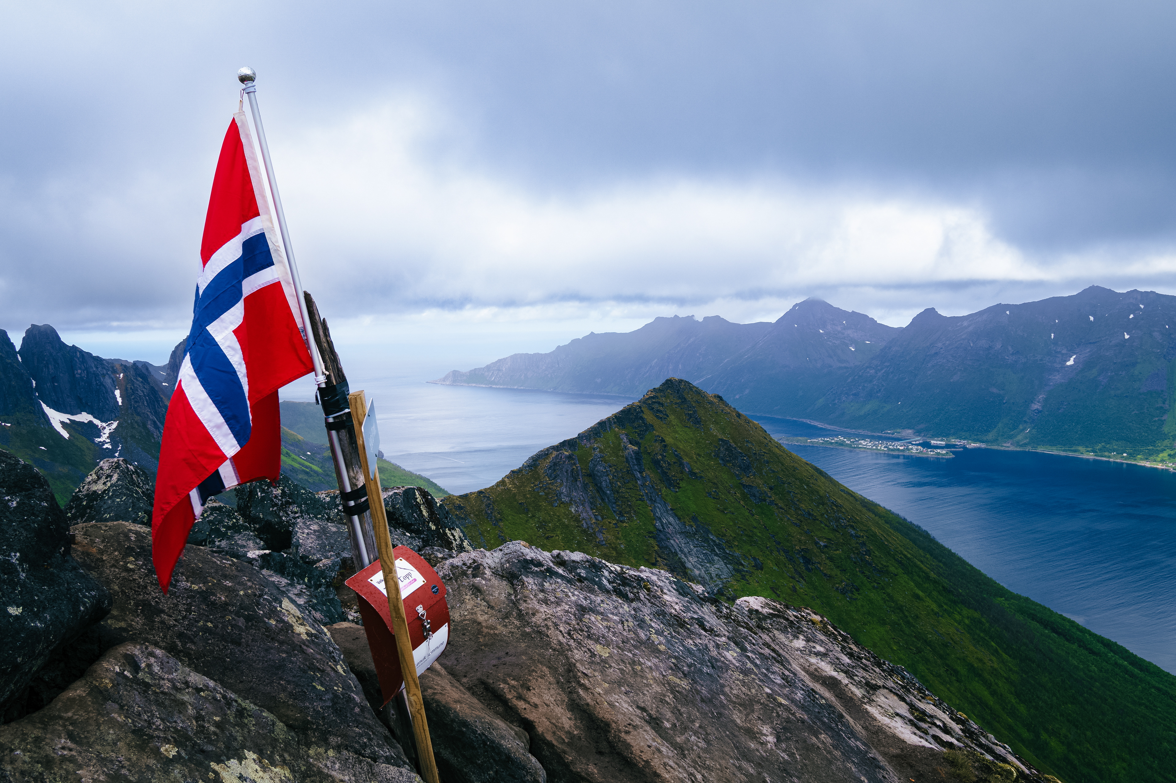 A Norwegian flag flies at the summit of Segla, an iconic mountain on the island of Senja