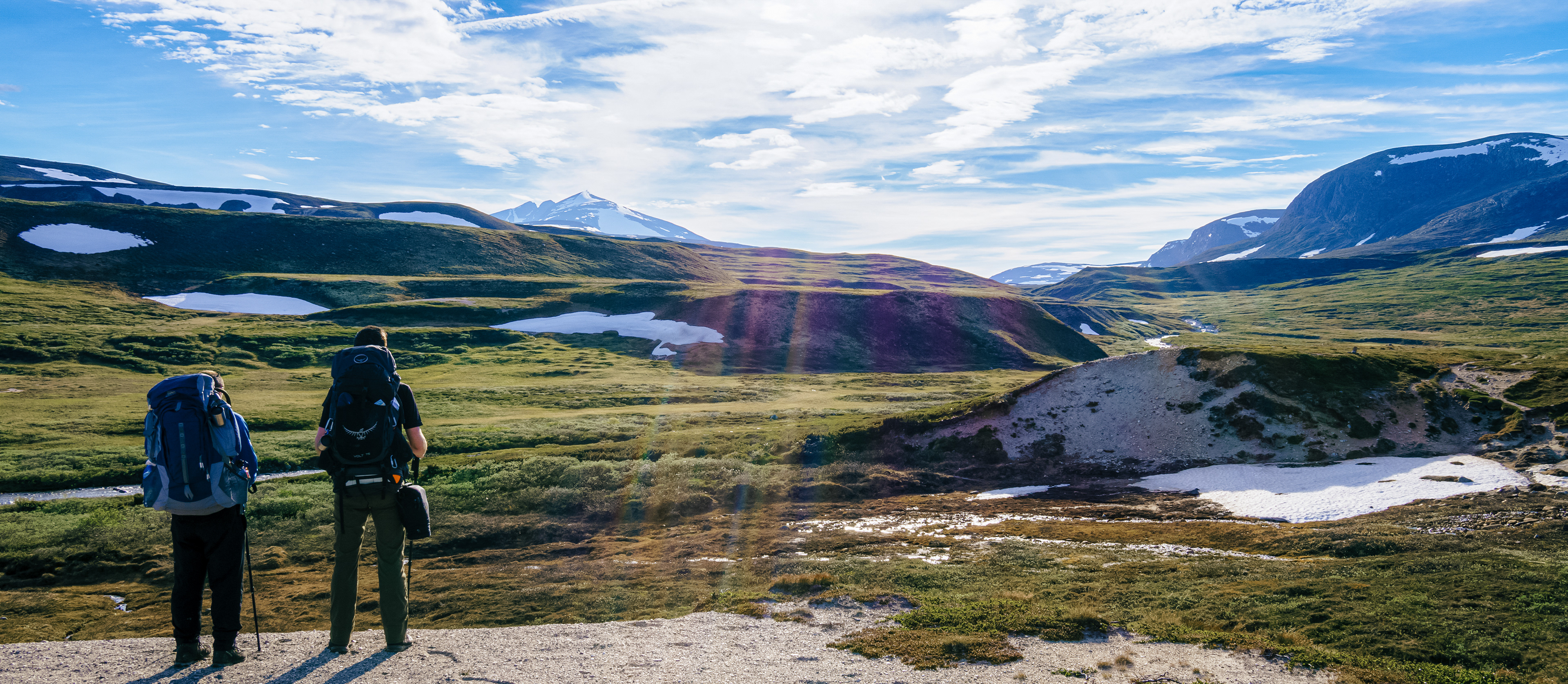 Nick and James pause to admire the distant peaks and warm sunbeams breaking through the cloud cover in Dovrefjell-Sunndalsfjella Nasjonalpark
