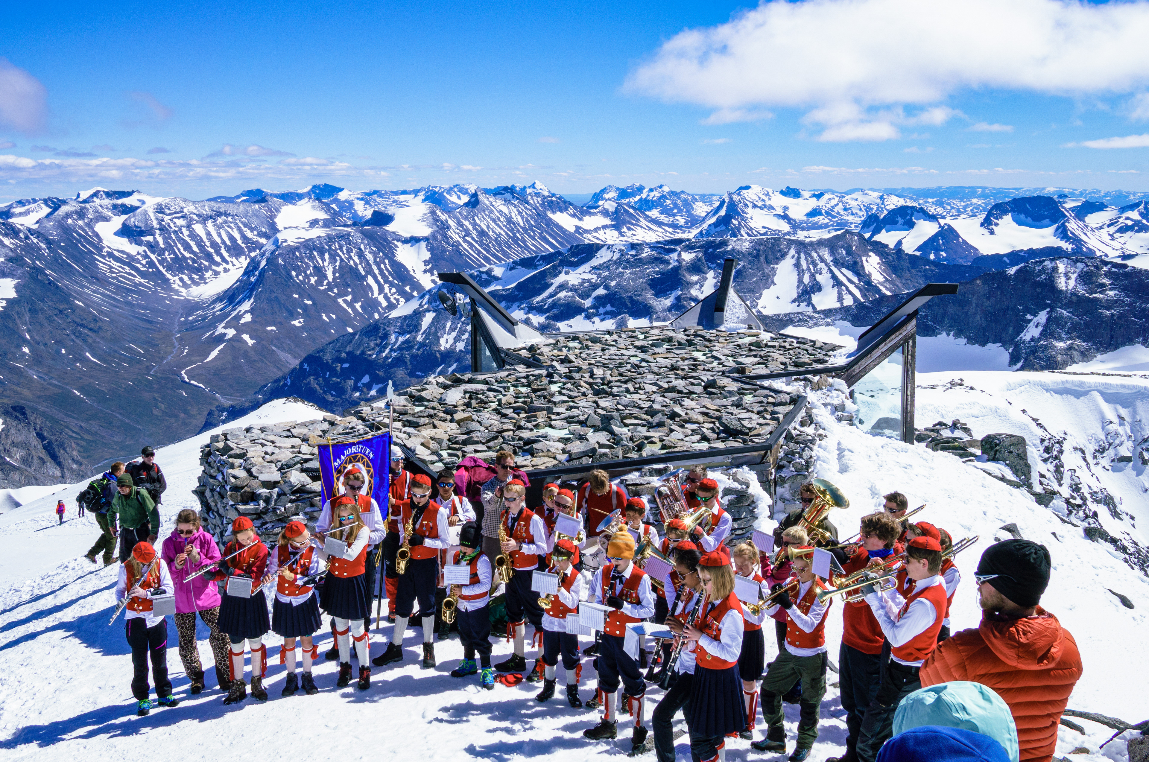 "So Much High!" A local school band plays traditional Norwegian marches at the summit of Galdhøpiggen. They hiked up a different route while carrying their instruments, trying to set a Guinness World Record.