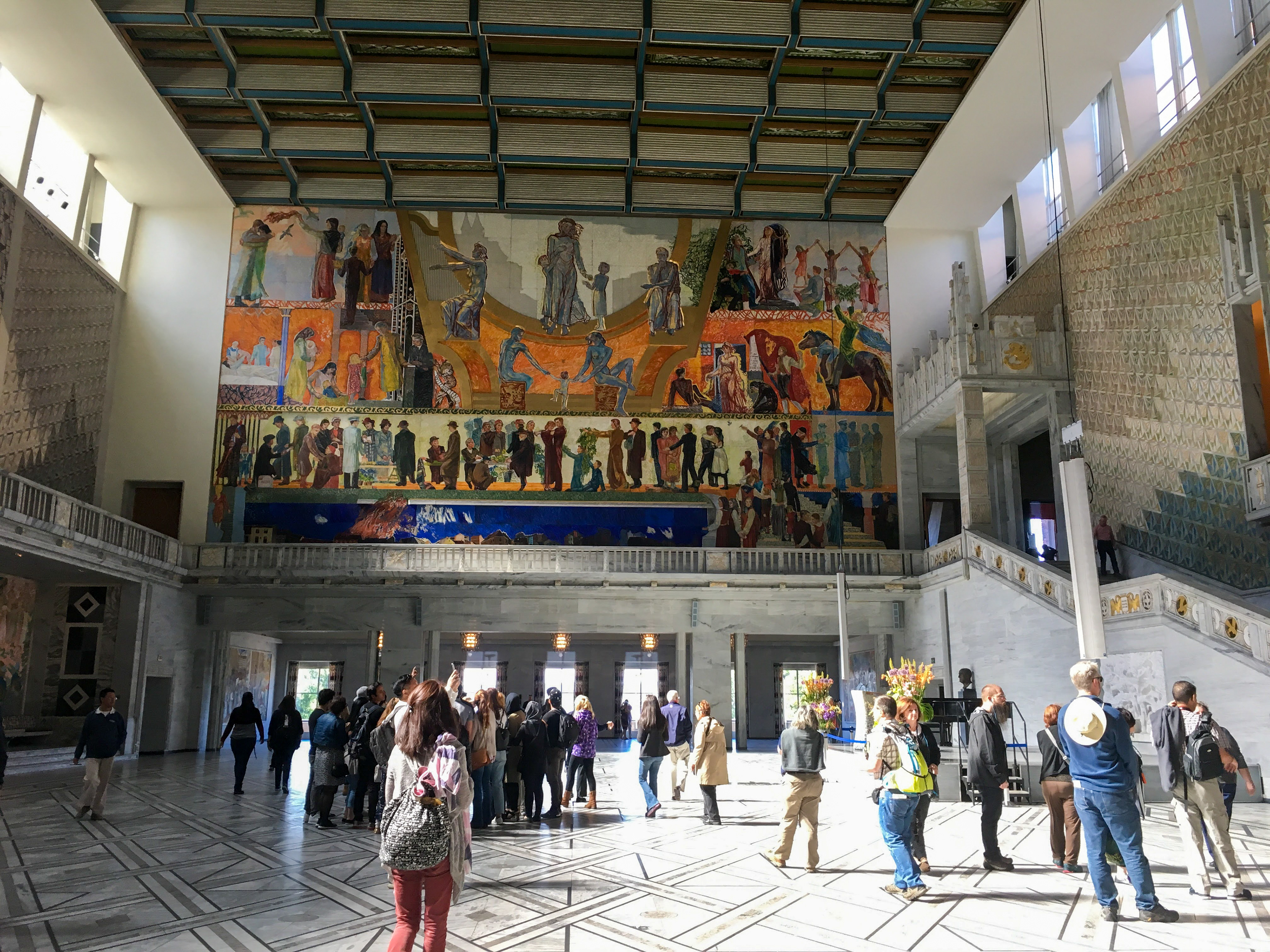 The main hall of Oslo City Hall. One wall is covered by a massive oil painting by Henrik Sørensen, titled "Arbeid, Administrasjon, Fest" ("Work, Administration, Celebration", alternatively "The Nation at Work and Play") c. 1938-1950