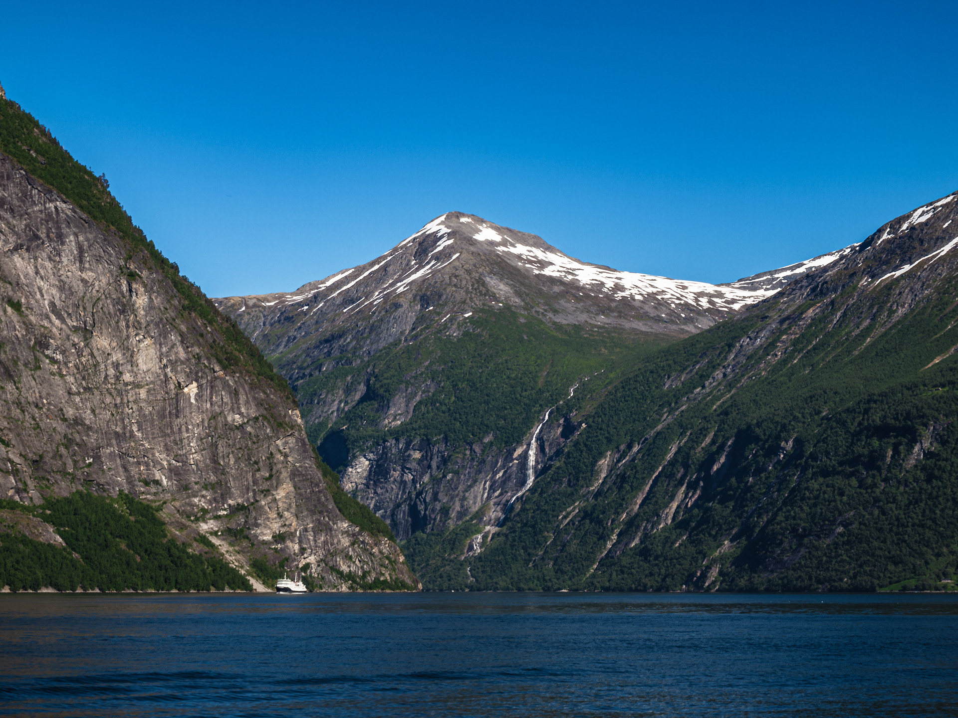 A snowcapped peak in the distance as viewed from the water of Geirangerfjord