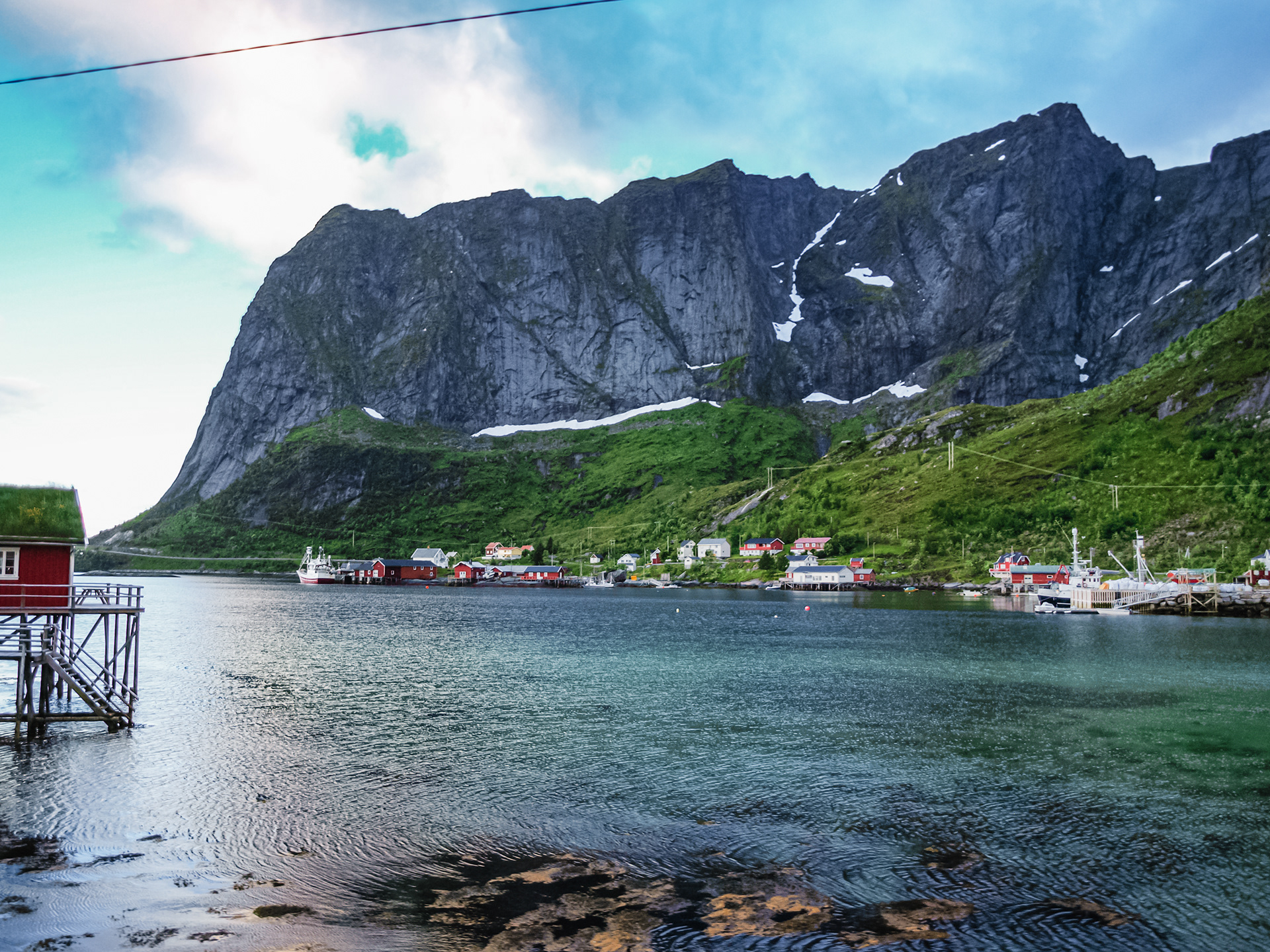 Jagged peaks dwarf the red houses built at the water's edge in Reine, Lofoten
