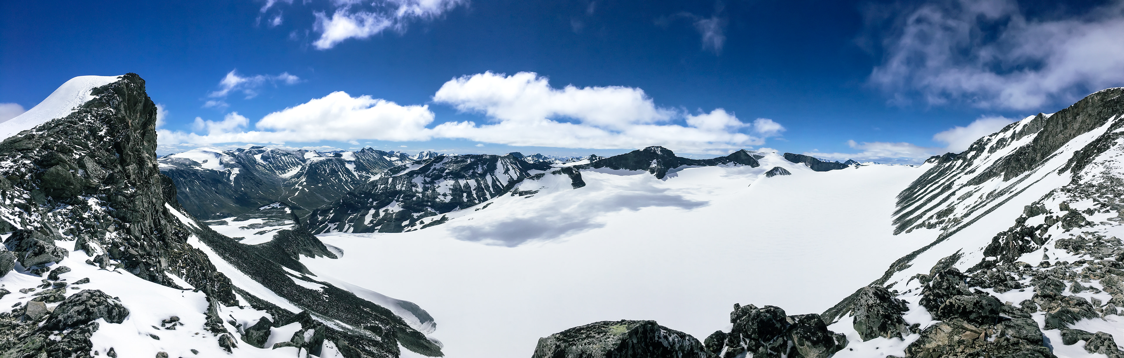 A panorama shows clouds appearing to fly low over a massive valley filled with snow and ice