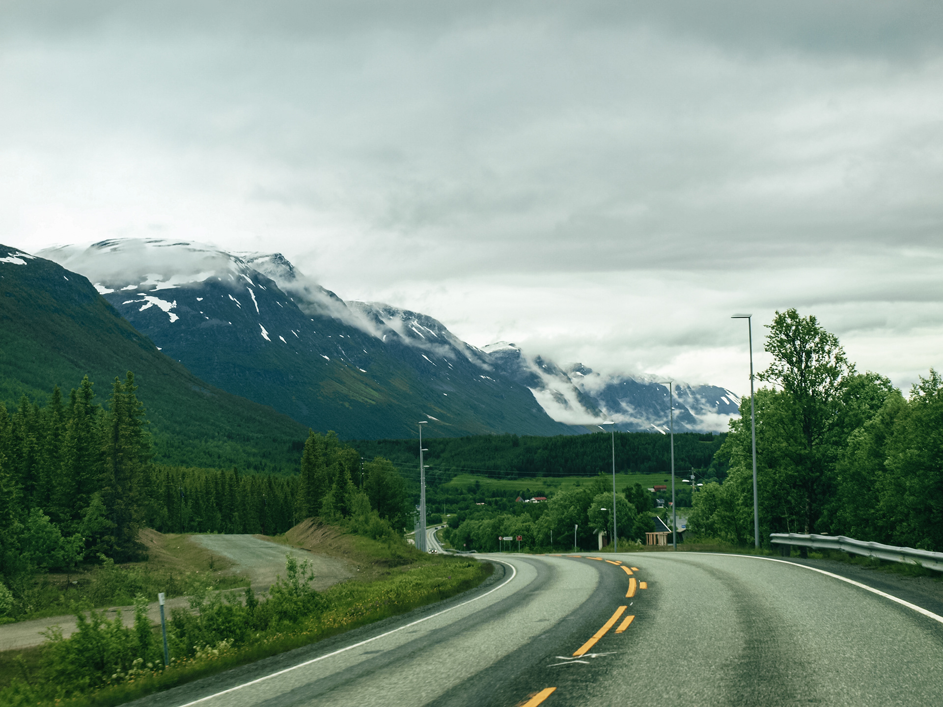 A winding road leads to mountains shrouded in mist on the road to Segla on the island of Senja